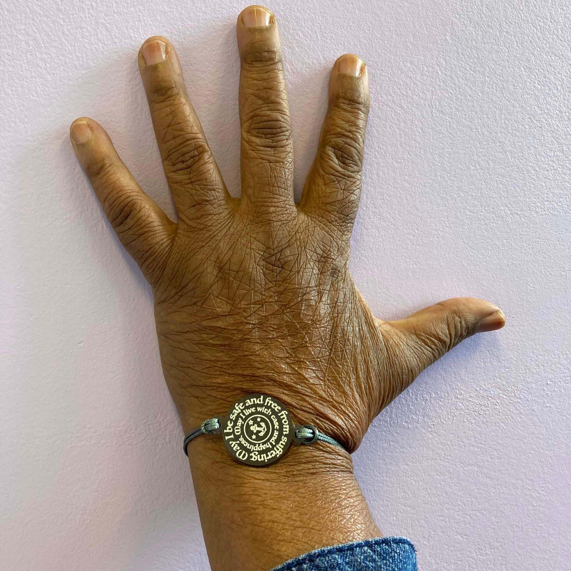 A member of Women for Refugee Women wears a May I Be Safe bracelet in shale from The Courage Collection, designed by Sarah Day for Wear and Resist. £2 goes to Women for Refugee Women.