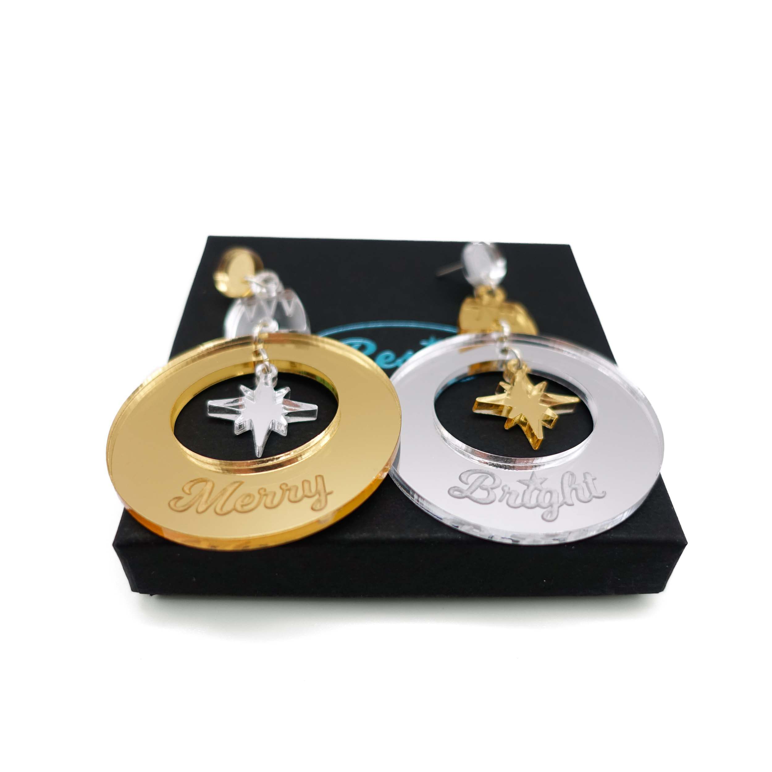 Merry & Bright Christmas bauble earrings in gold and silver mirror, shown on a Wear and Resist gift box.