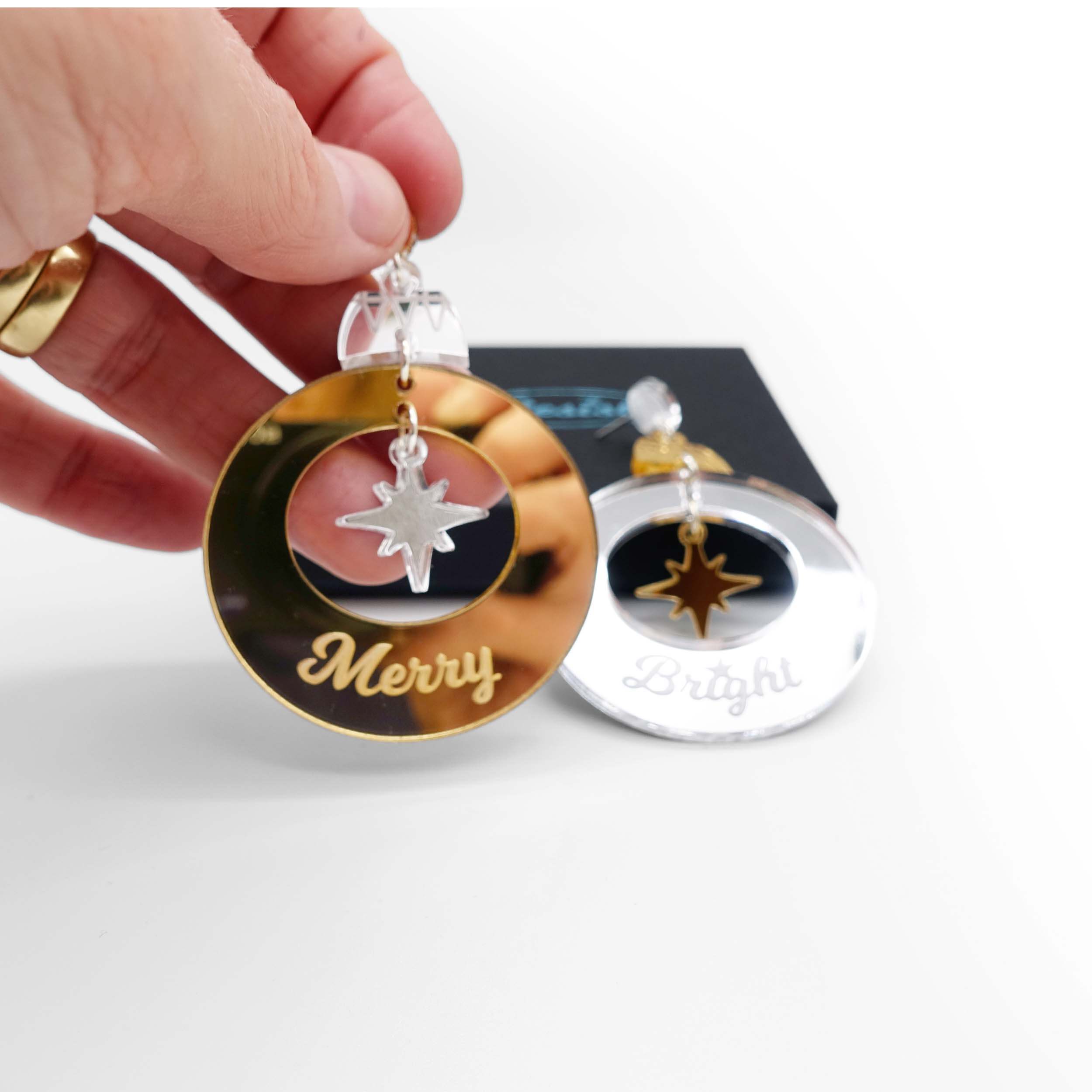 Merry & Bright Christmas bauble earrings in gold and silver mirror, shown held in my hand for scale with a Wear and Resist gift box in the background.