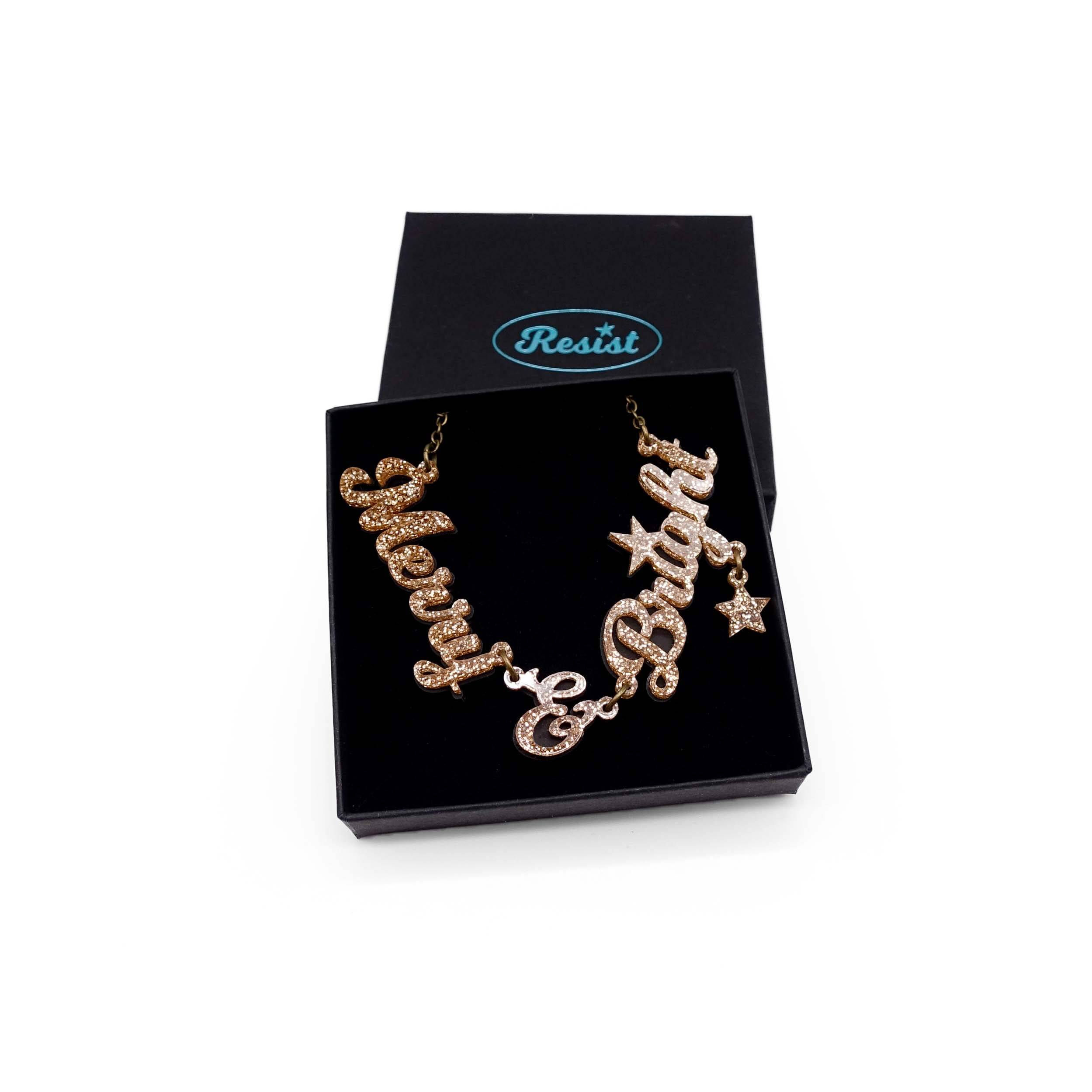 Merry & Bright necklace in gold glitter on an antique gold chain, shown in a Wear and Resist gift box.