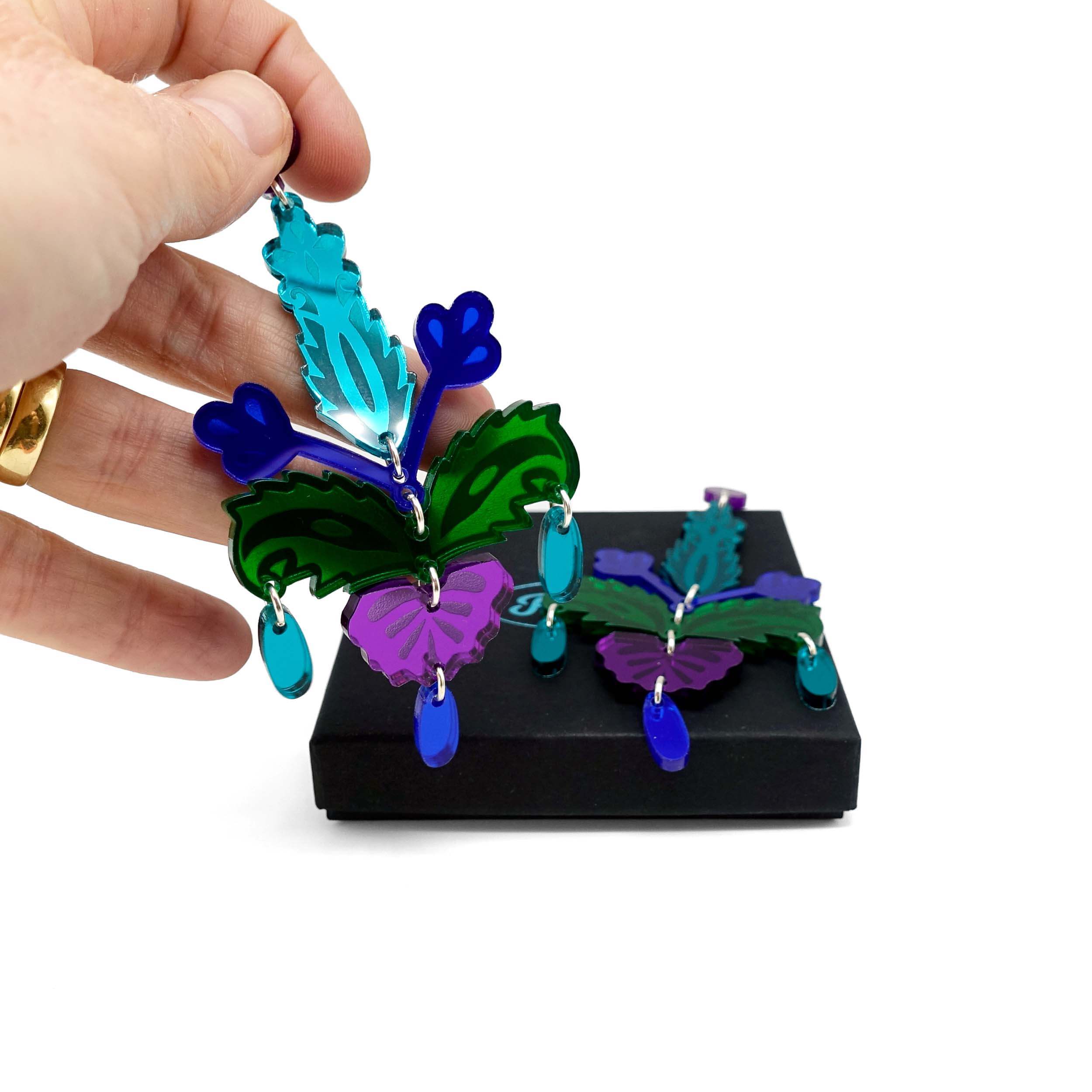 Midnight Festive Drop statement earrings shown being picked up from a Wear and Resist gift box.