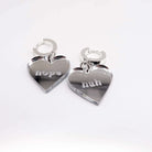 Nah Nope heart shaped huggie hoop earrings in silver mirror shown sitting on a white surface.