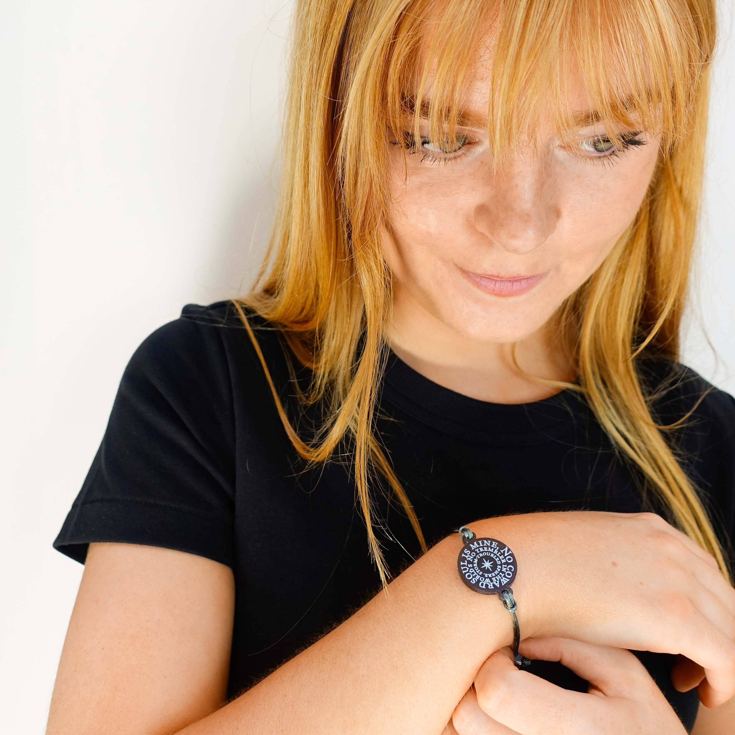 Eliza wears the No Coward Soul is Mine hand-tied bracelet from the Brontë Collection, etched with the first two lines of Emily Brontë's poem.