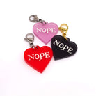 Heart charms in chilli frost, pink frost and slate frost etched in glow-in-the-dark pigment with the word 'Nope'