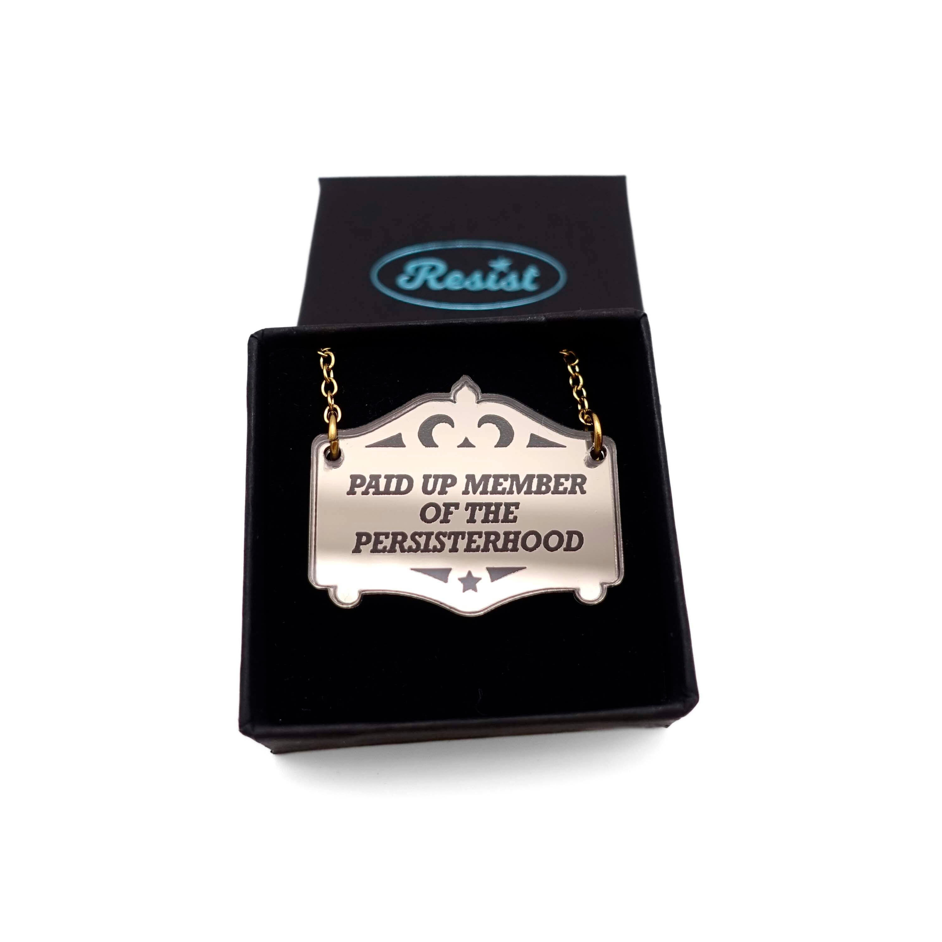 A bronze Paid up member of the Persisterhood necklace, shown in a small Wear and Resist gift box.