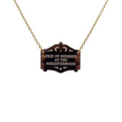 A bronze Paid up member of the Persisterhood necklace, shown hanging on a gold-plated stainless steel chain.