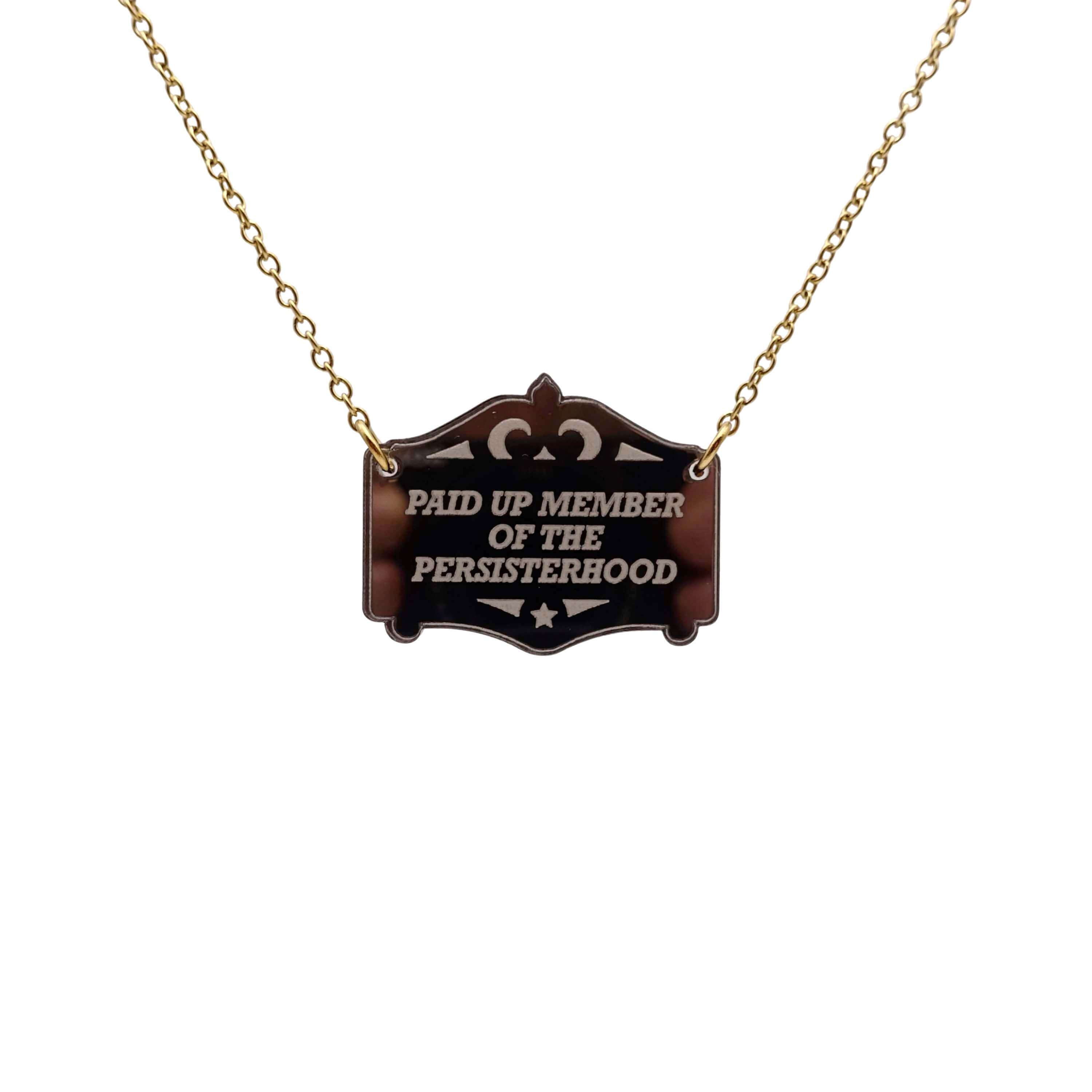 A bronze Paid up member of the Persisterhood necklace, shown hanging on a gold-plated stainless steel chain.