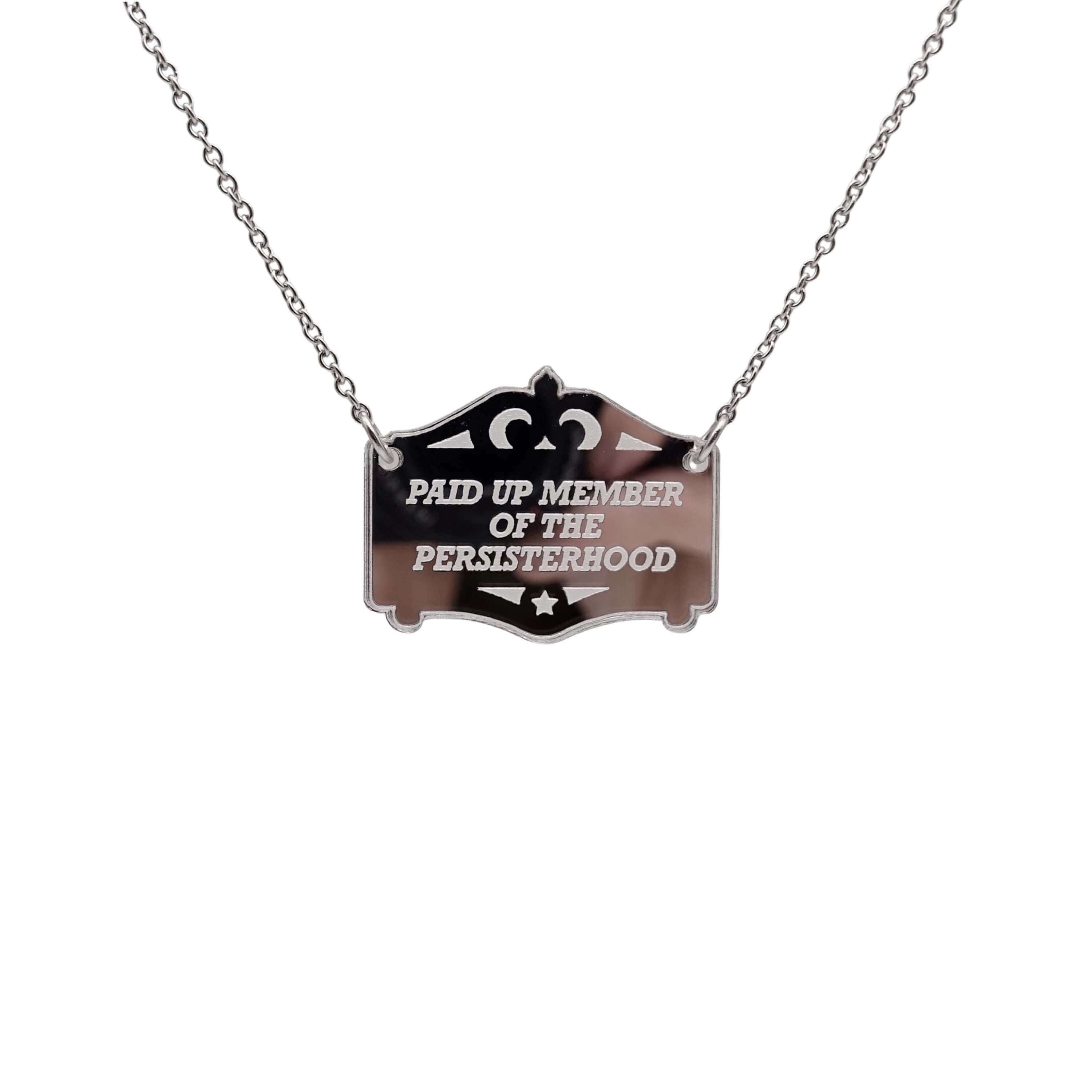 A silver Paid up member of the Persisterhood necklace, shown hanging on a stainless steel chain.