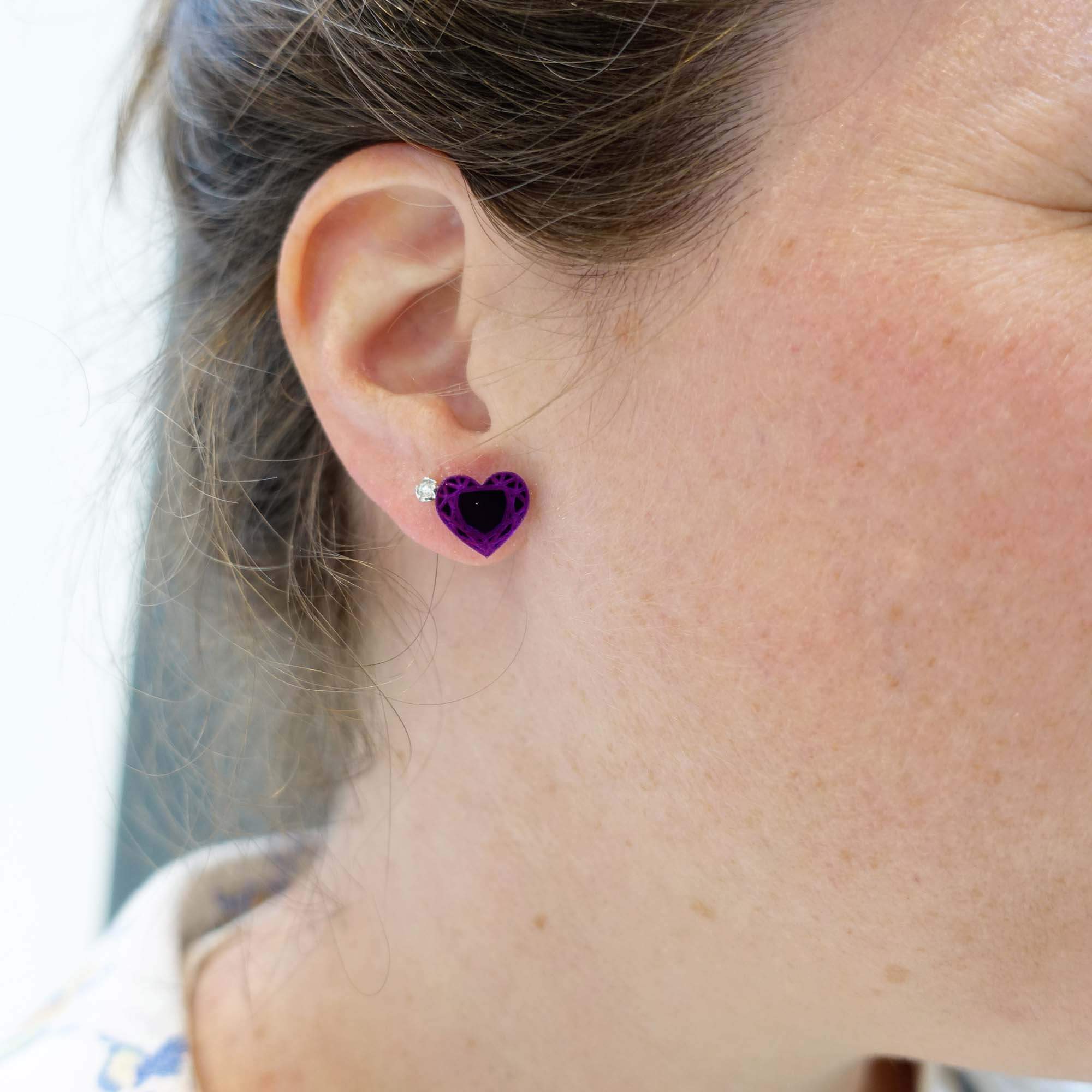 Faye wears purple heart stud earrings from the Suffragette Collection at Wear and Resist.