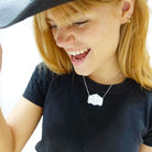 Eliza wears a Rage, rage against the Lying of the Right mirror cowboy necklace in silver on a stainless steel chain.
