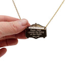 Rage, rage against the Lying of the Right mirror cowboy necklace in bronze, shown hanging on a gold-plated stainless steel chain with my hand for scale.
