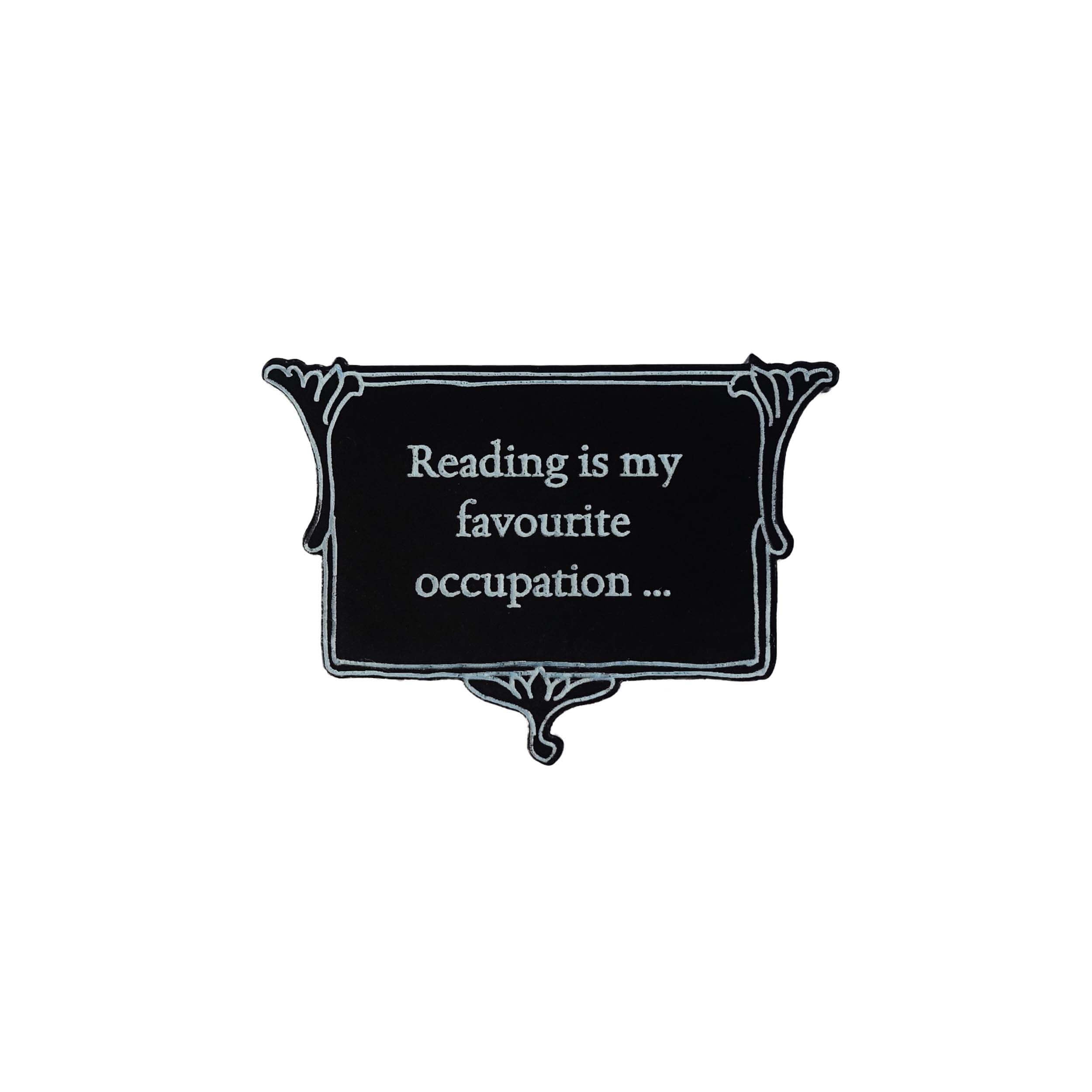 A matte black brooch etched with glow-in-the-dark pigment that says,  'Reading is my favourite occupation ...' a quote from Anne Brontë's Agnes Grey. It is part of The Brontë Collection at Wear and Resist.
