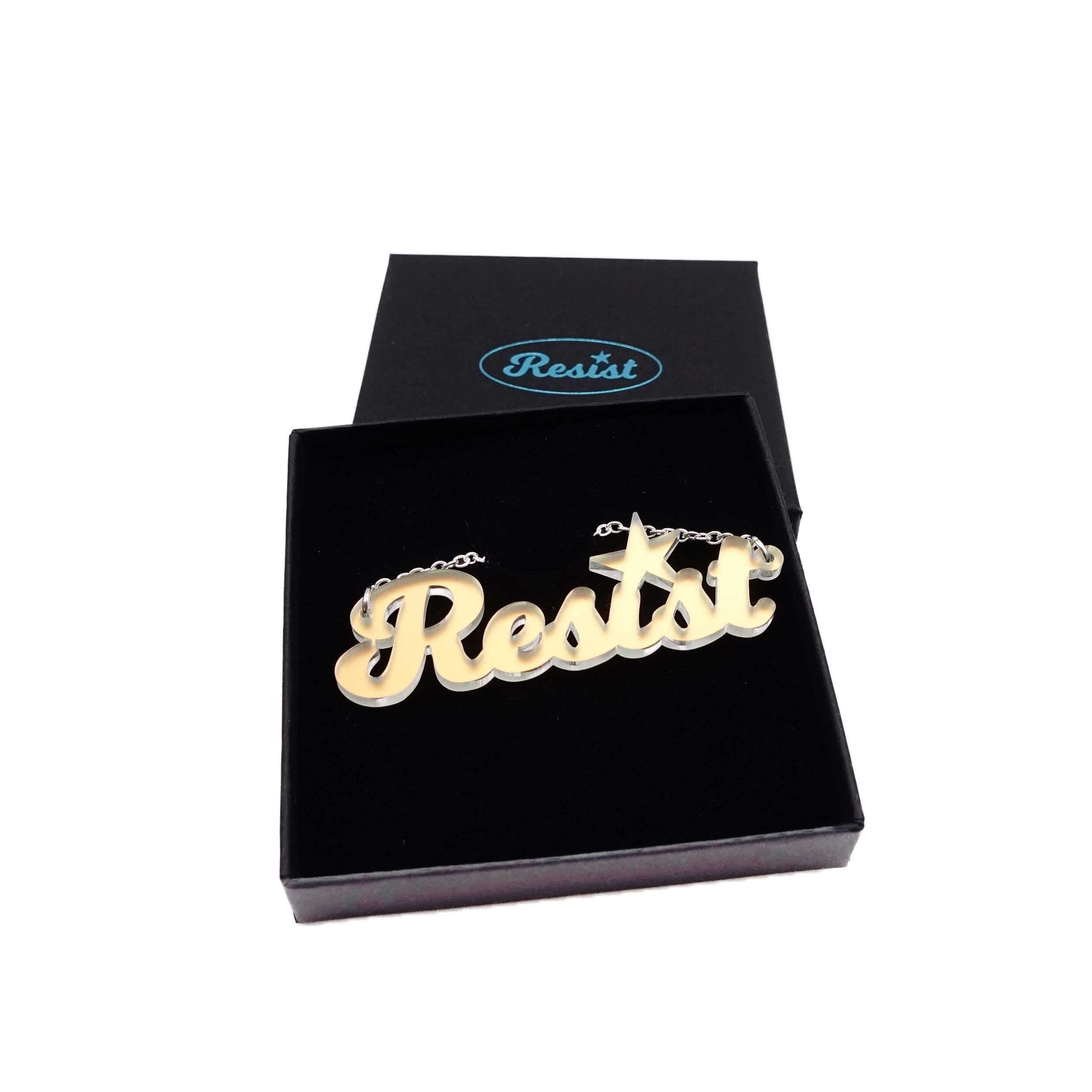 A 'Resist' necklace in matte iridescent shown in a Wear and Resist gift box.