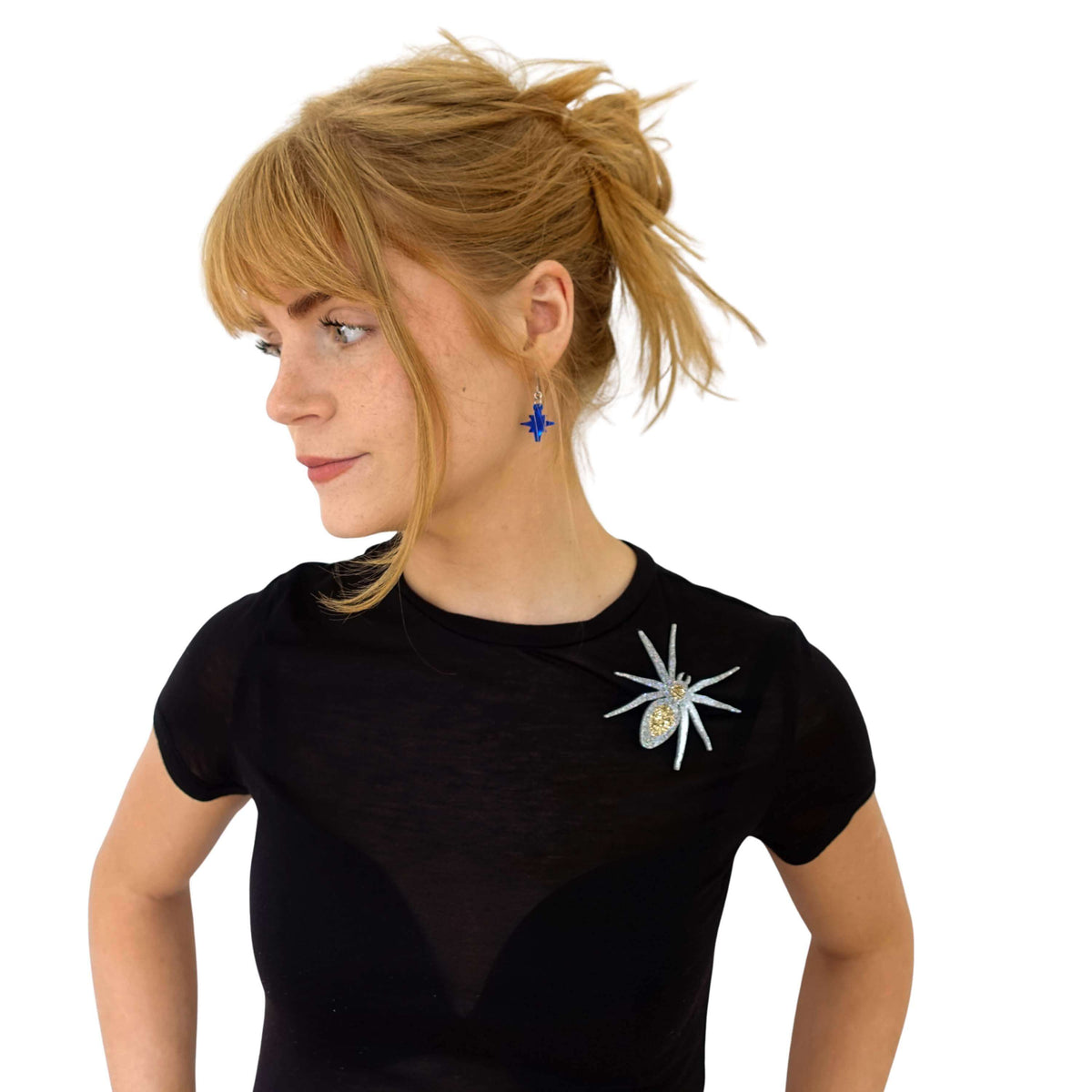 Eliza wears a spider brooch on a t shirt