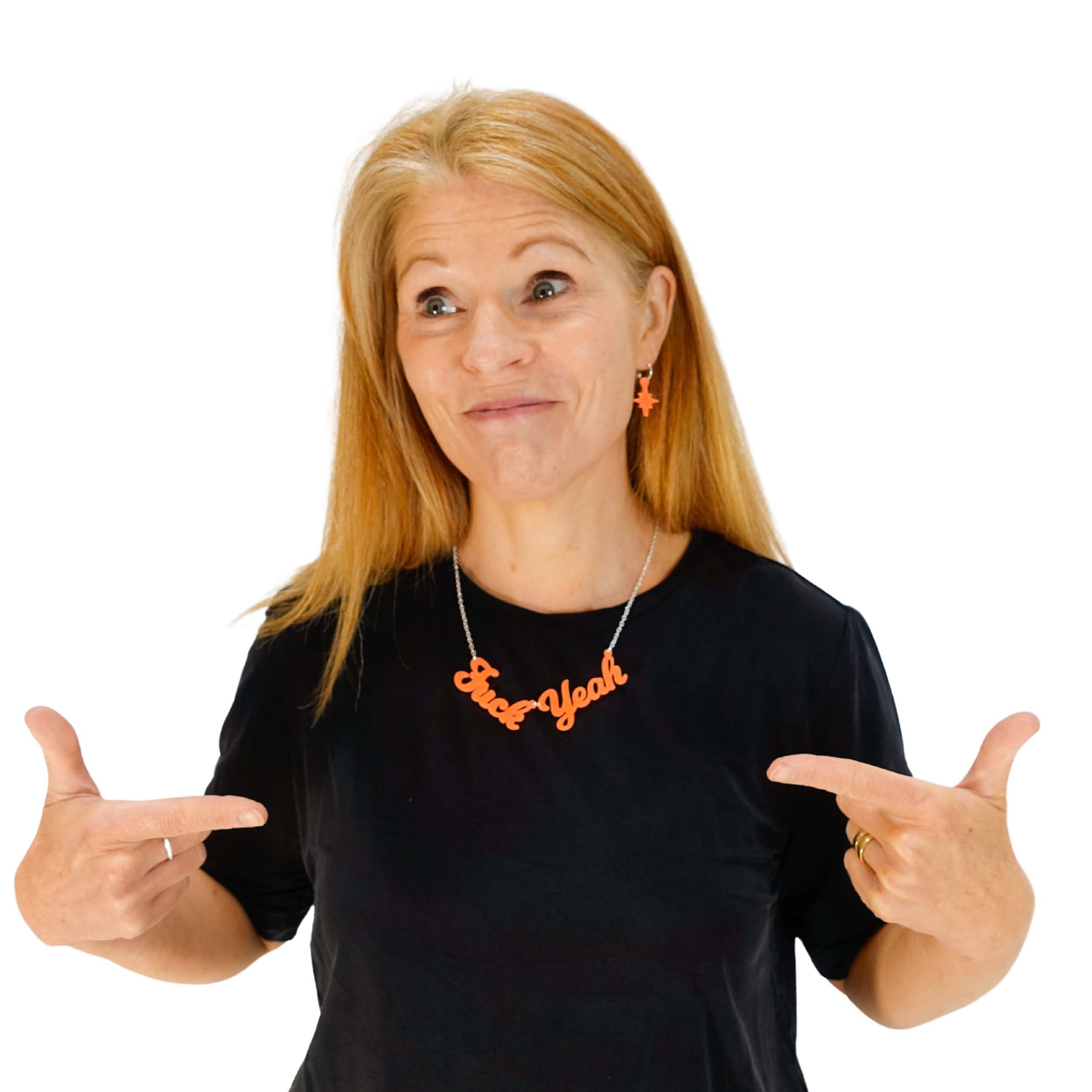 Sarah Day, founder of Wear and Resist wears a F*ck Yeah necklace day-glo orange with matching vintage star hoop earrings.