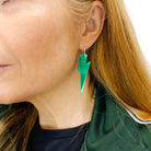 Sarah wears large lightning bolt hoop earrings in electric green.