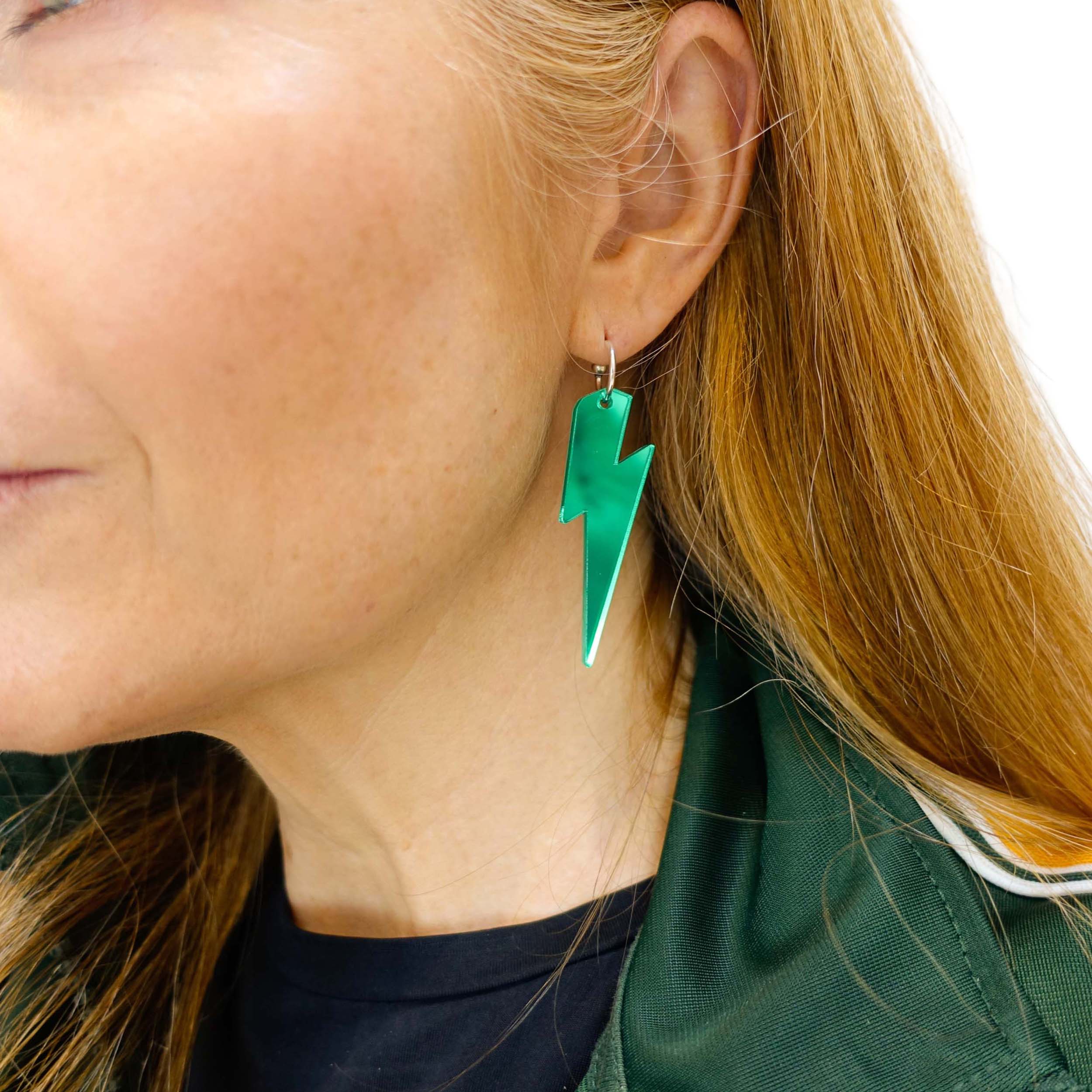 Sarah wears large lightning bolt hoop earrings in electric green.