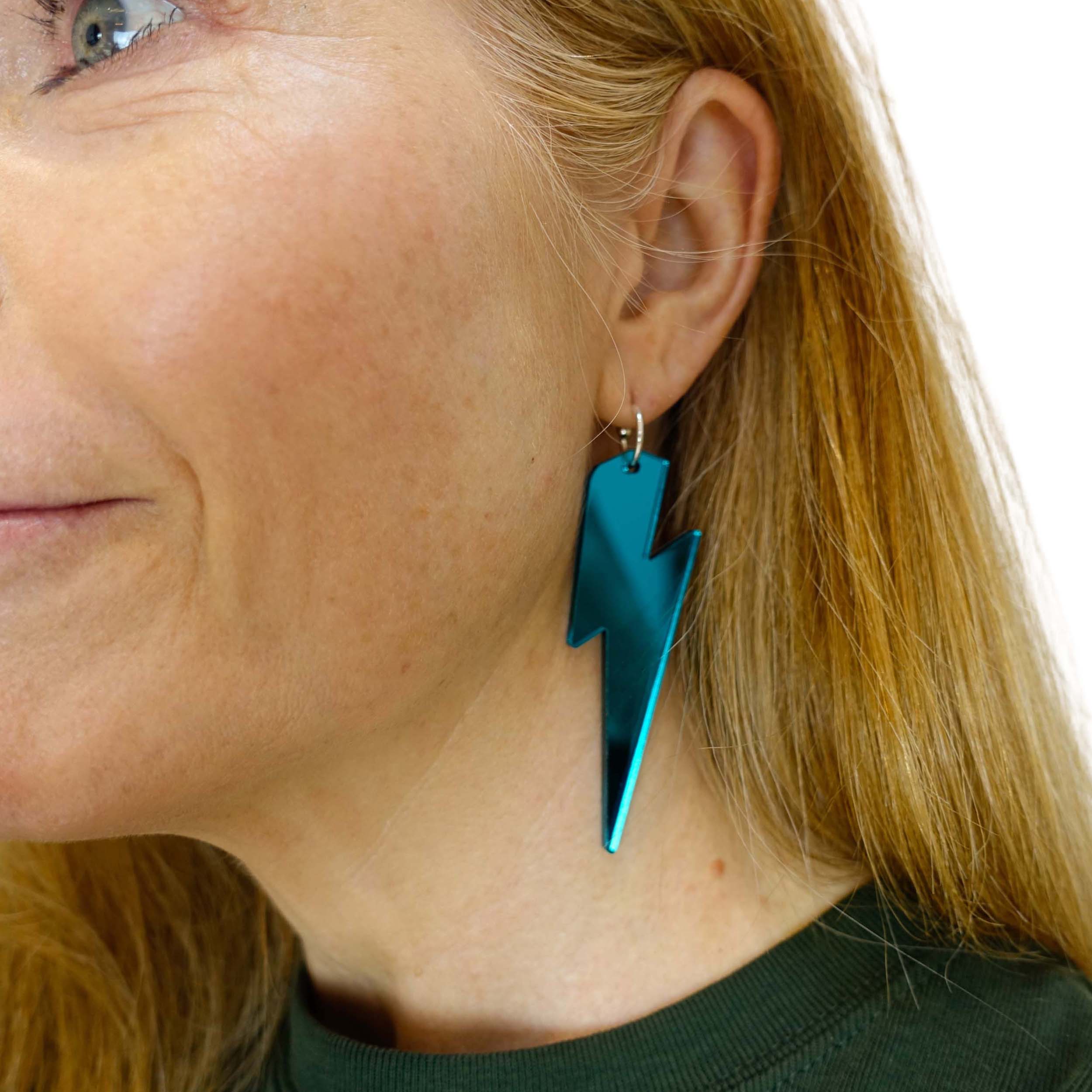 Sarah wears massive Lightning Bolt hoop earrings in teal mirror.
