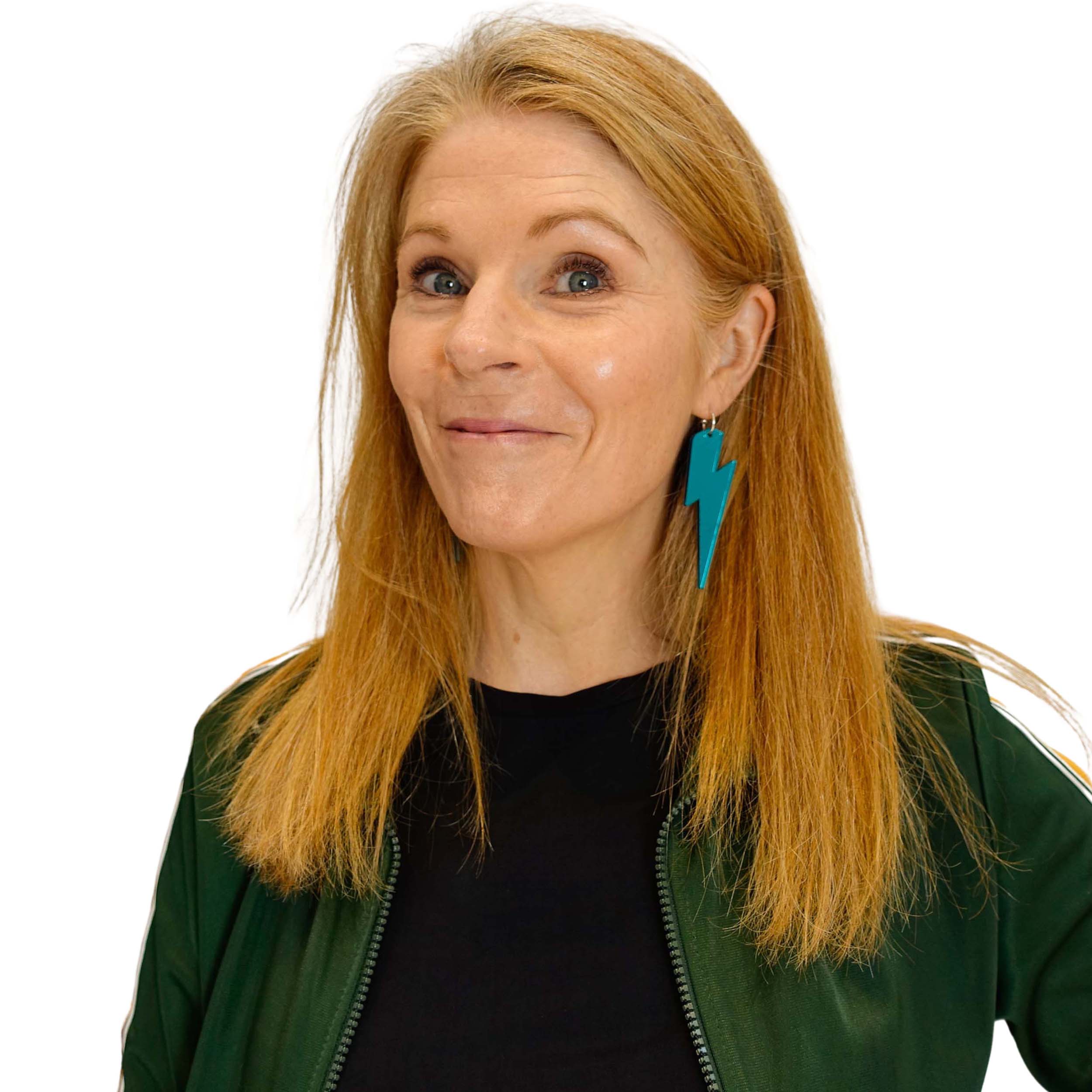 Sarah wears massive Lightning Bolt hoop earrings in teal mirror.