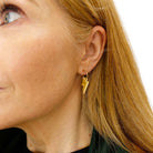 Sarah wears small gold mirror lightning bolt hoops on gold plated hoops.