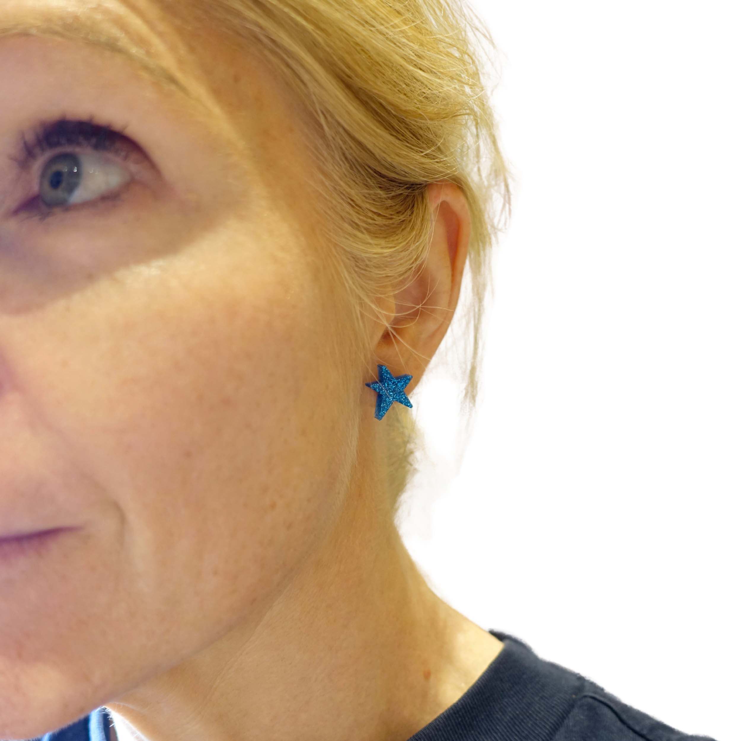 Sarah wears funky Resist star earrings in blue glitter.
