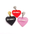 Heart charms in chilli frost, pink frost and slate frost etched in glow-in-the-dark pigment with the word 'Shero'