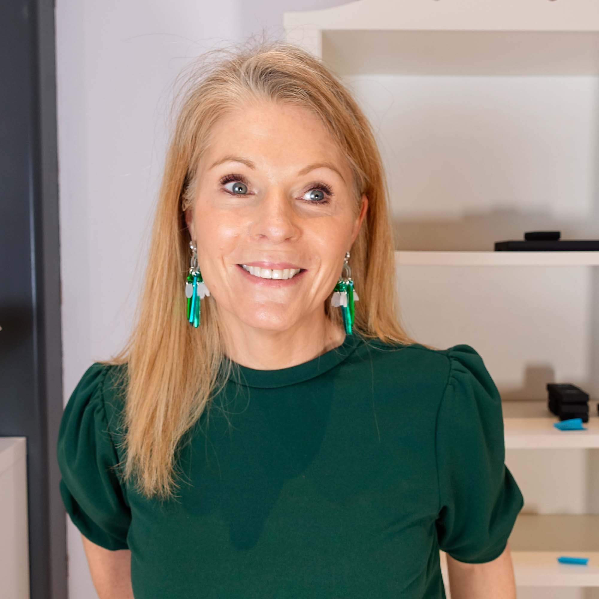 Sarah smiling wearing Snowdrop earrings in her studio.