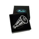 Matte black small megaphone brooch etched in glow-in-the-dark pigment with the words There is Still Hope. Shown in a small Wear and Resist gift box.