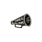Matte black small megaphone brooch etched in glow-in-the-dark pigment with the words There is Still Hope.