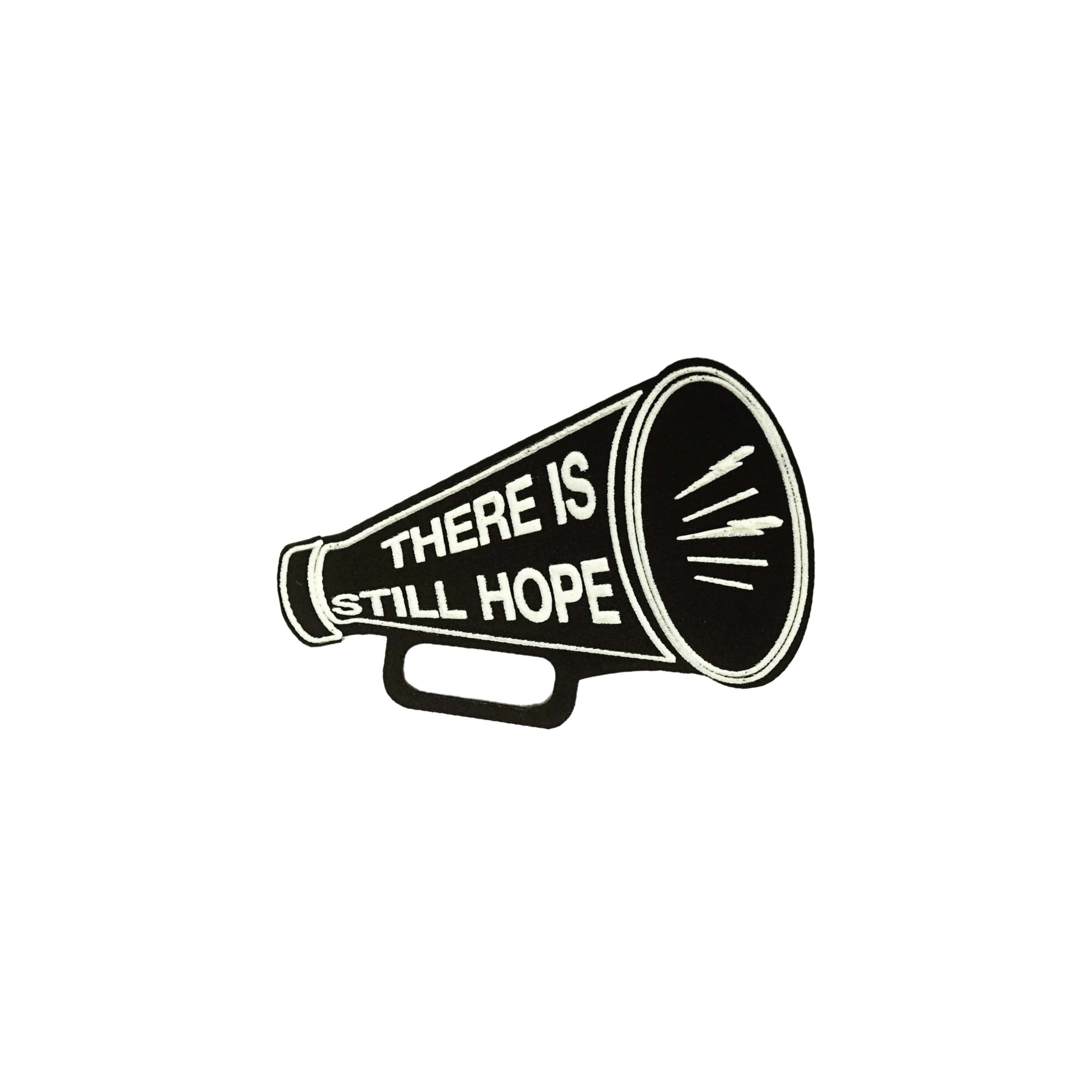 Matte black small megaphone brooch etched in glow-in-the-dark pigment with the words There is Still Hope.