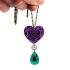 A pendant necklace with a purple heart-shaped pendant inscribed with 'Take Courage' and a silver and green jewel drop on an antique gold chain.