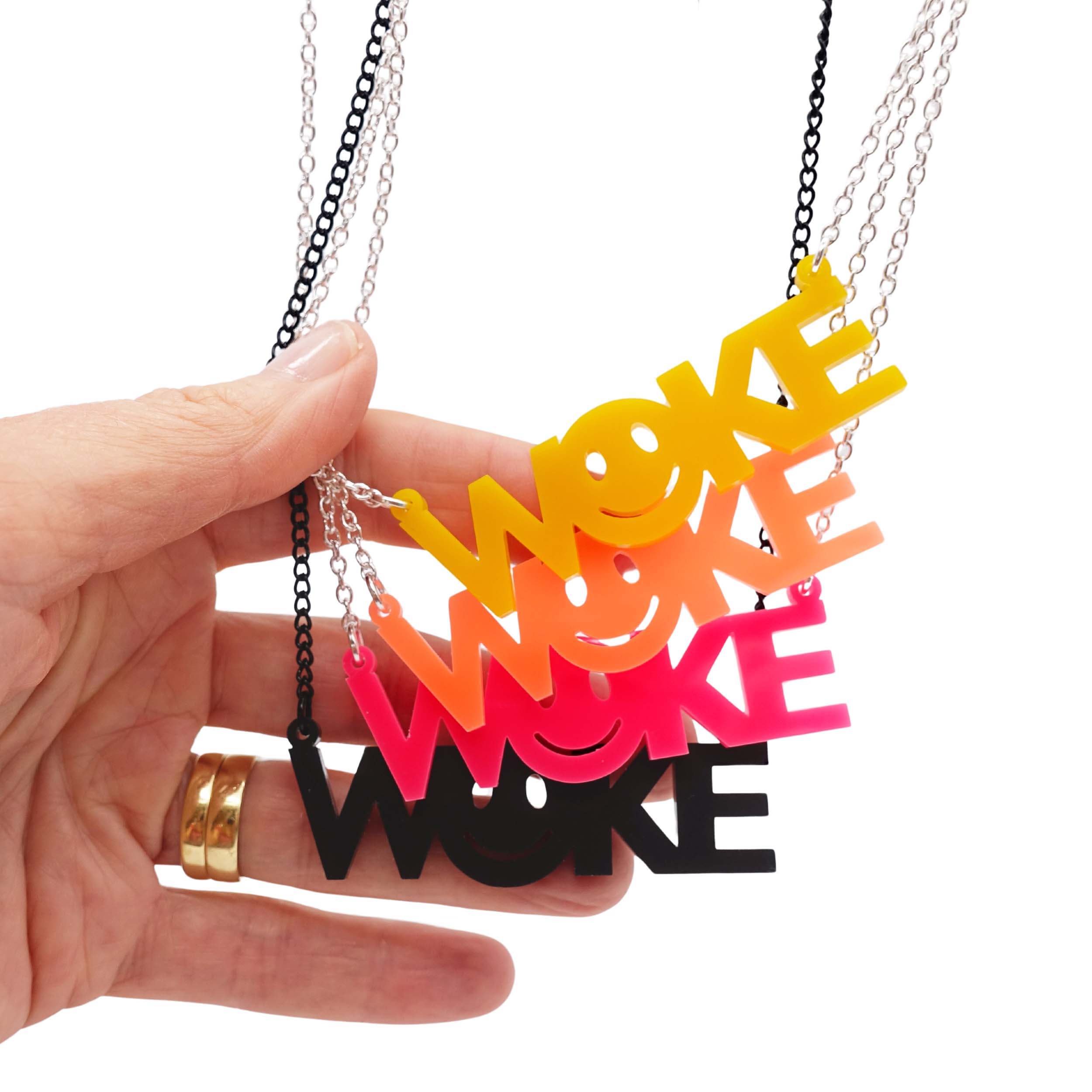 The four colours of WOKE necklaces shown hanging with my hand for scale.