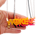 A group of WOKE necklaces shown hanging with my hand for scale with yellow in front.
