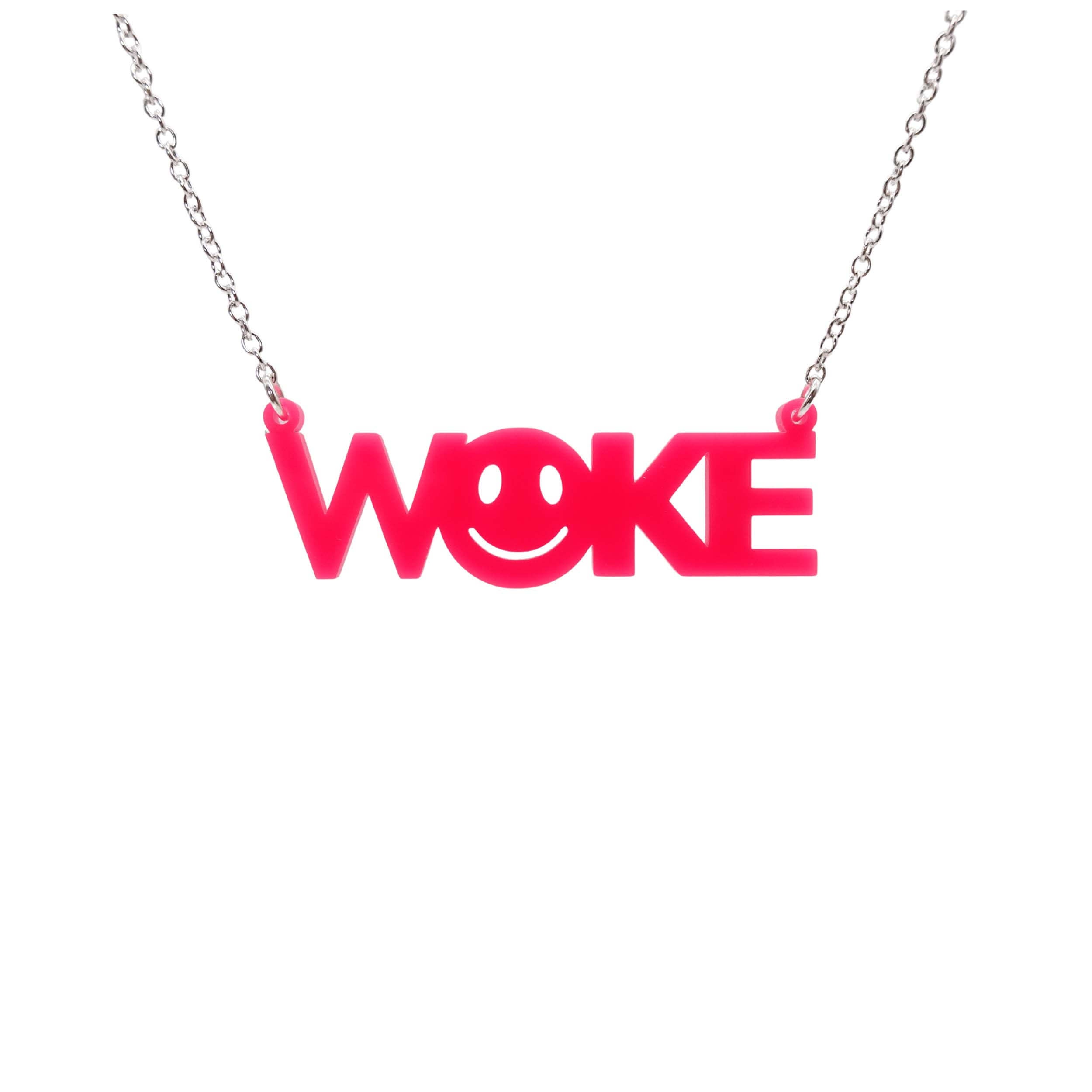 A hot pink WOKE necklace with a 90s smiley face cut out of the O shown hanging against a white background.