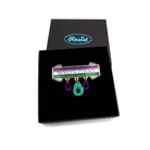 A brooch made in acrylic to look like etched bronze with the words Women Count and As Much as Men etched on the three bands in the Suffragette colours, with jewels hanging down in green and purple.