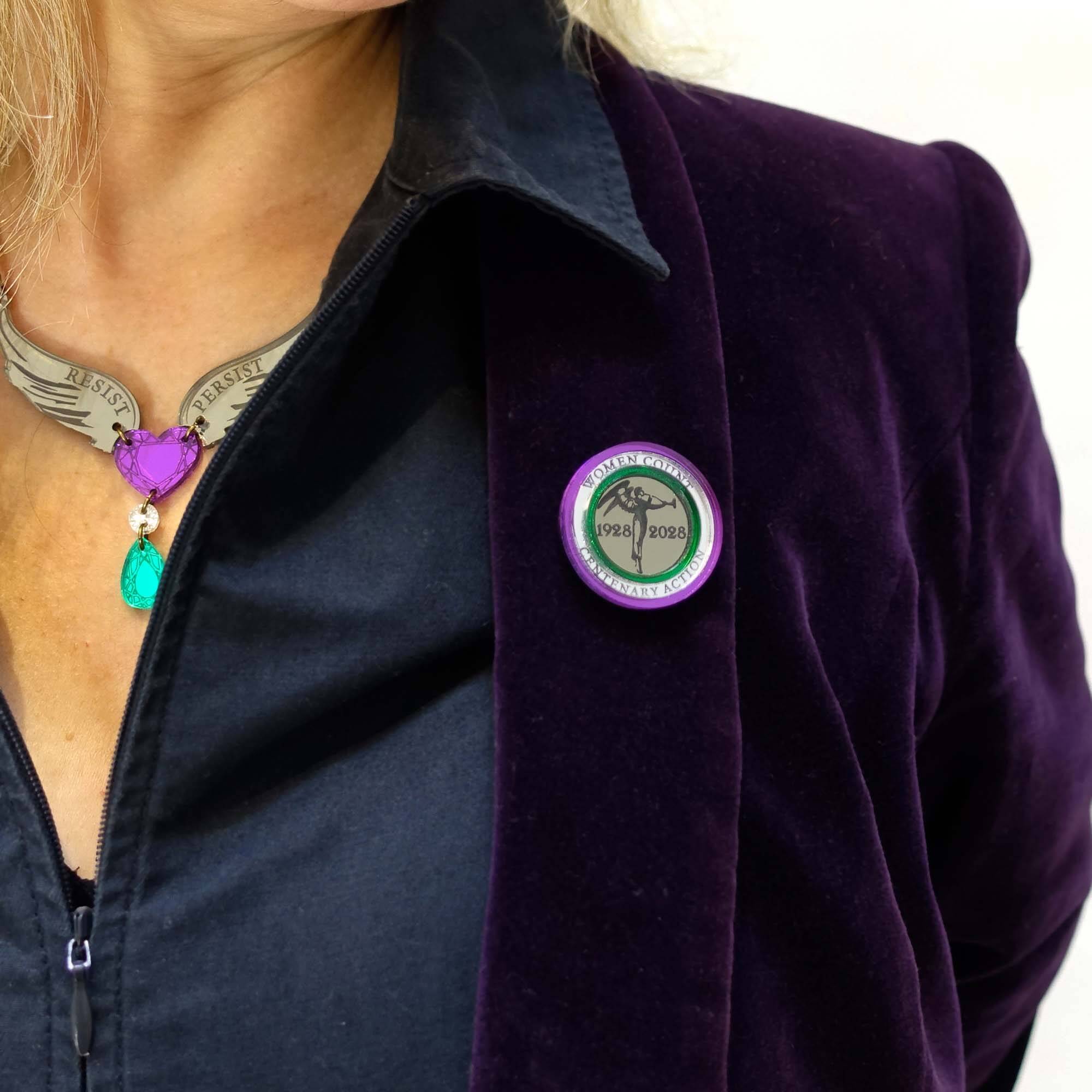 Andrea wears the Centenary Action round brooch with a Resist Persist Winged Heart necklace.