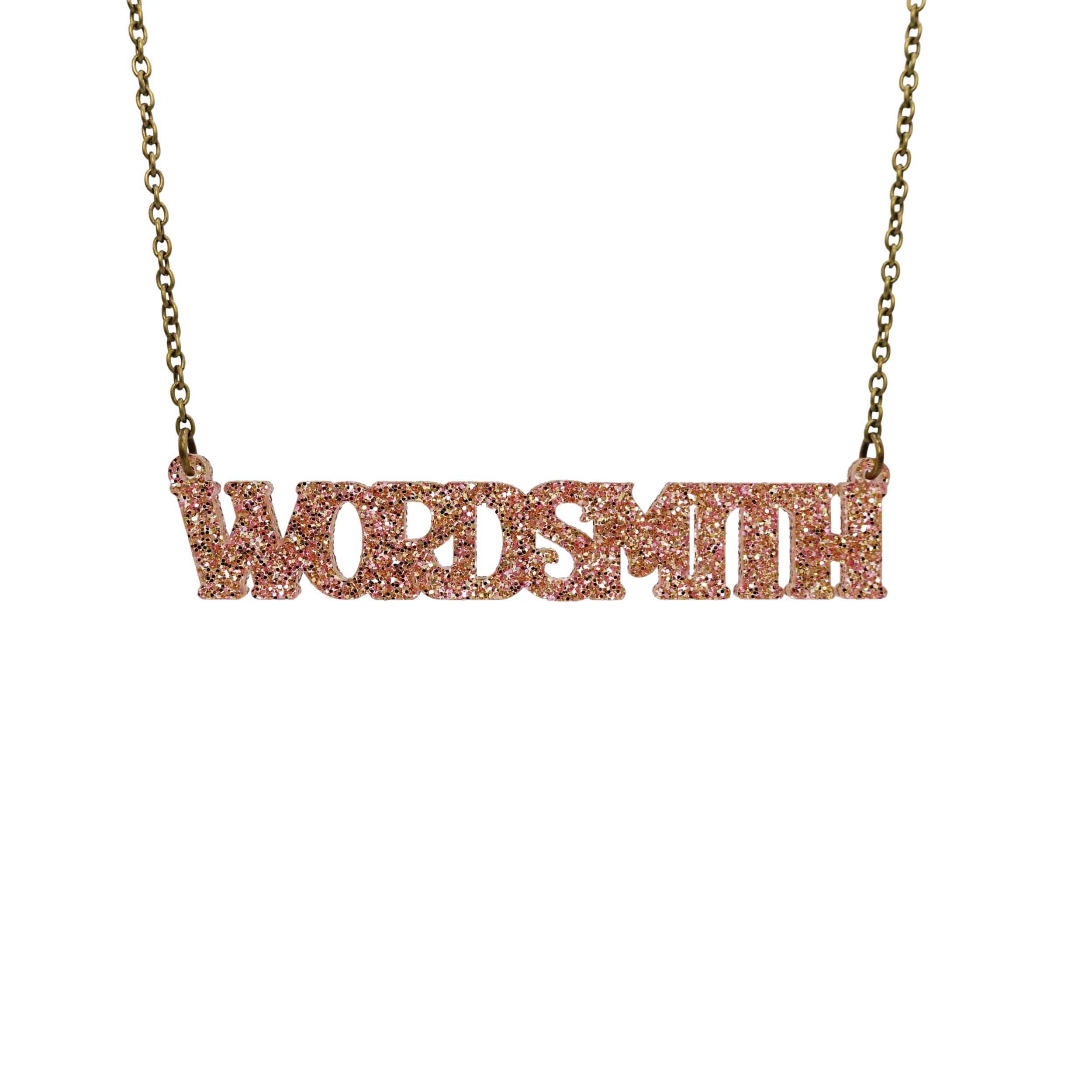 Wordsmith necklace in pink fizz glitter shown hanging against a white background.