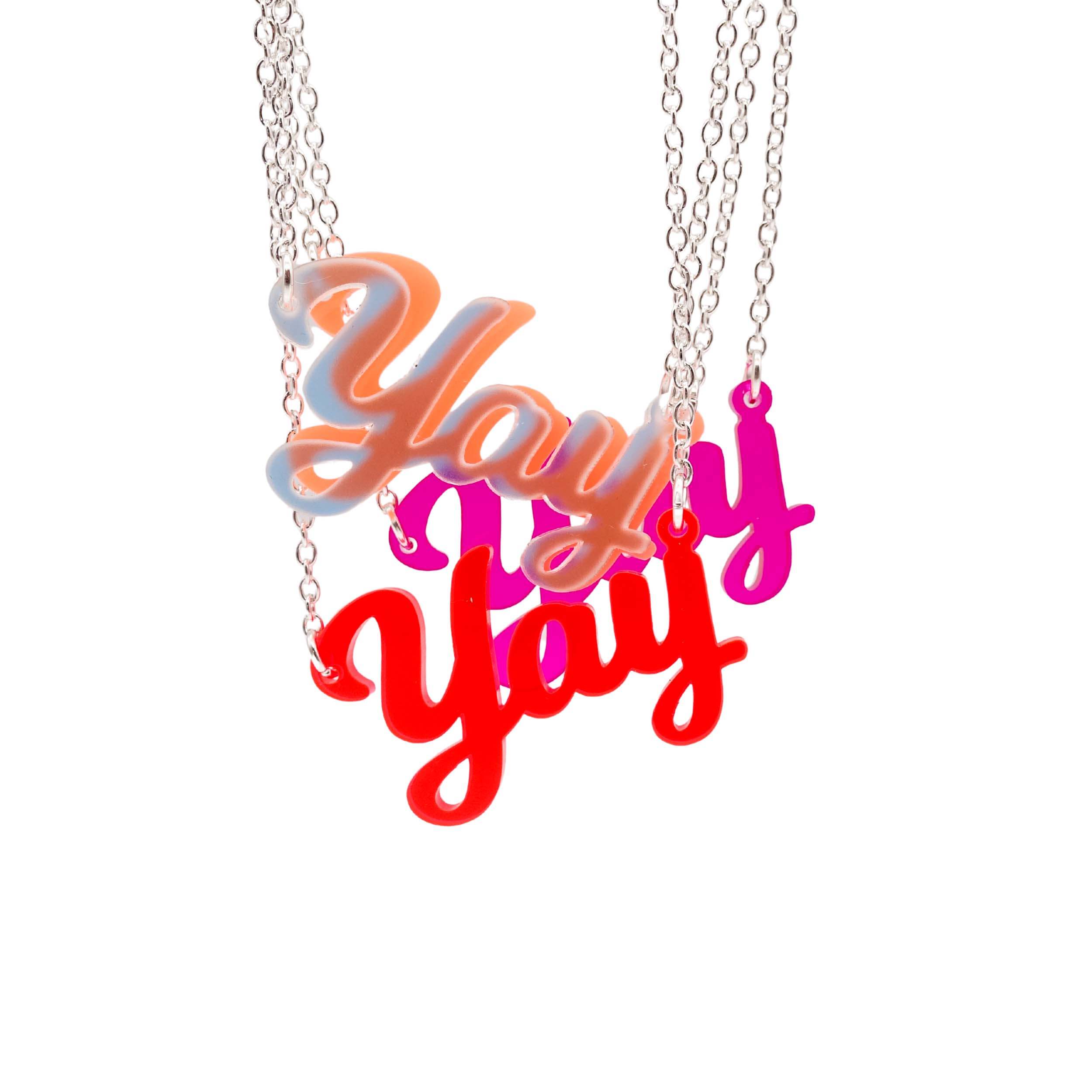 A group of Yay necklaces with matte iridescent in front shown hanging against a white background.