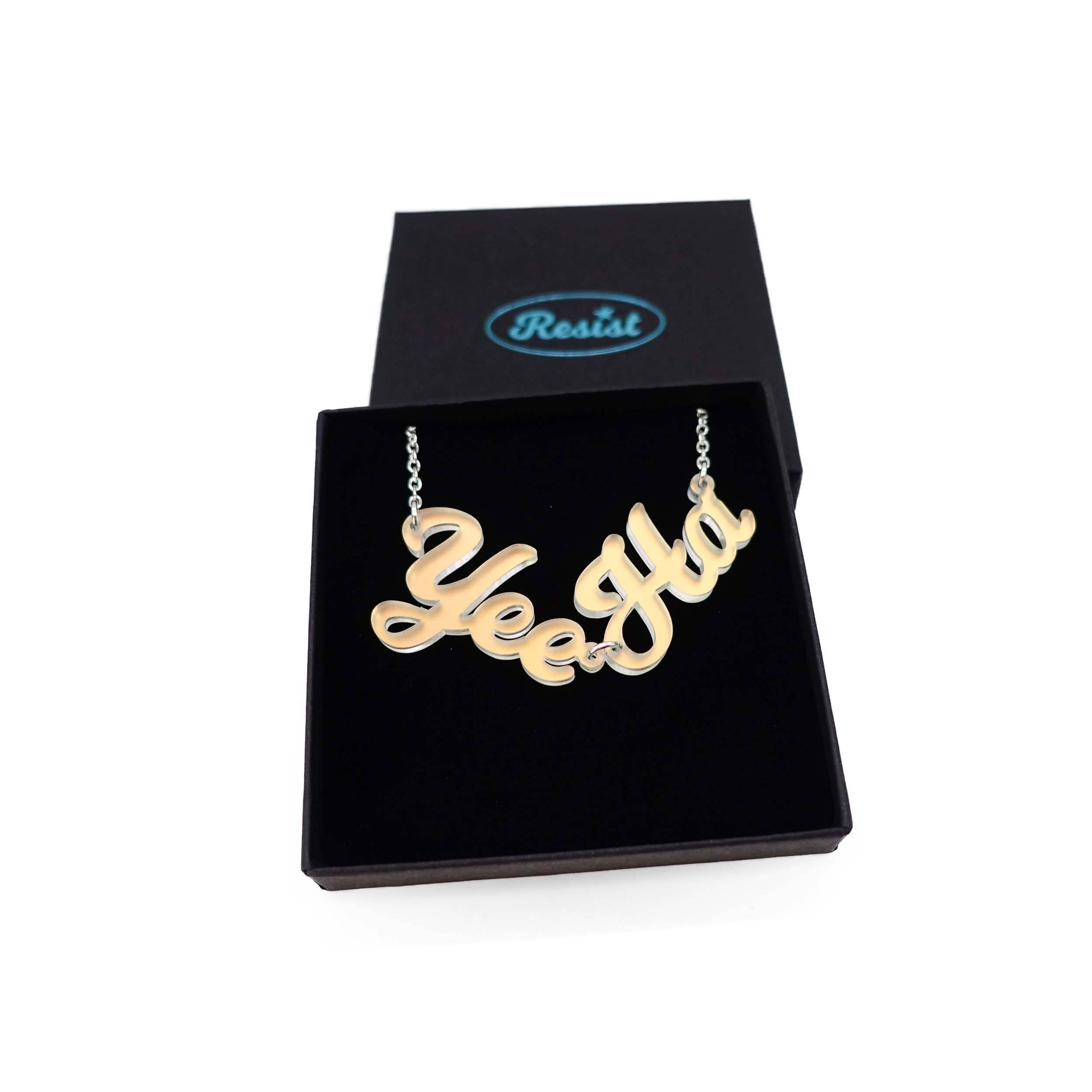 A matte iridescent Yee Ha necklace shown in a Wear and Resist gift box.