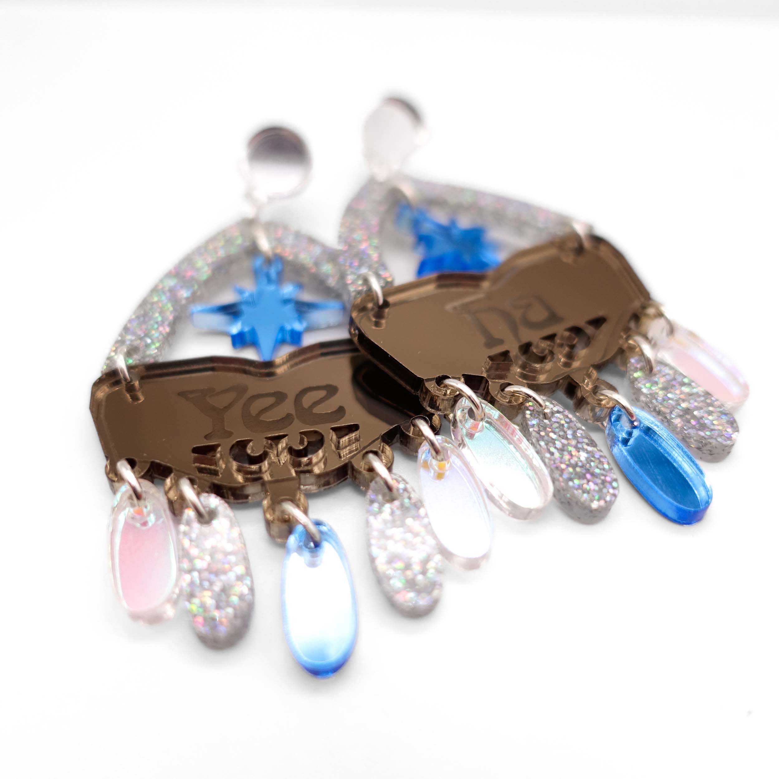 A close up of the Sky Cowgirl colourway of Western inspired Yee Ha earrings in bronze, sky, silver glitter and iridescent.