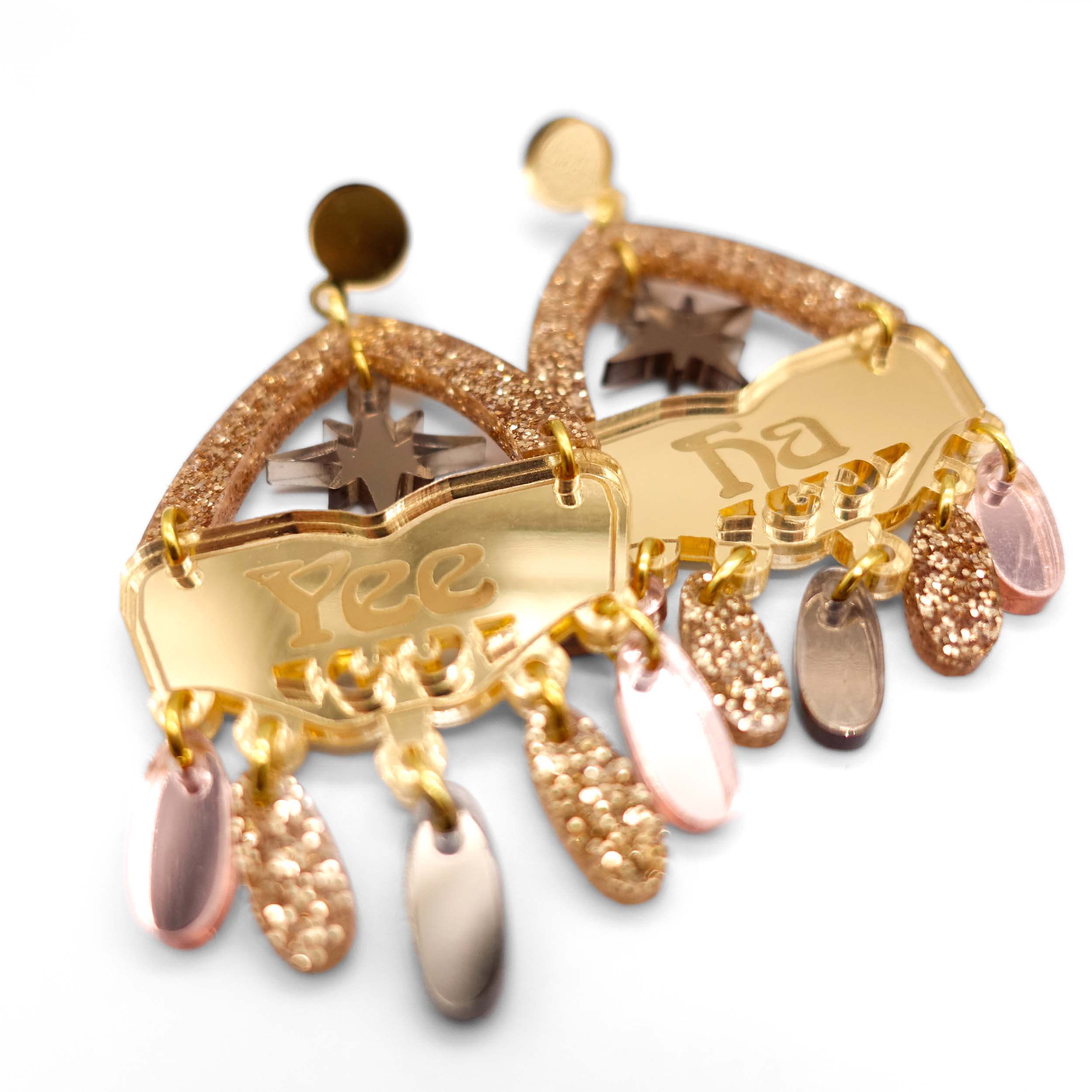 A close up of the Golden colourway Western style statement earrings in gold and bronze with the words Yee Ha engraved on them.
