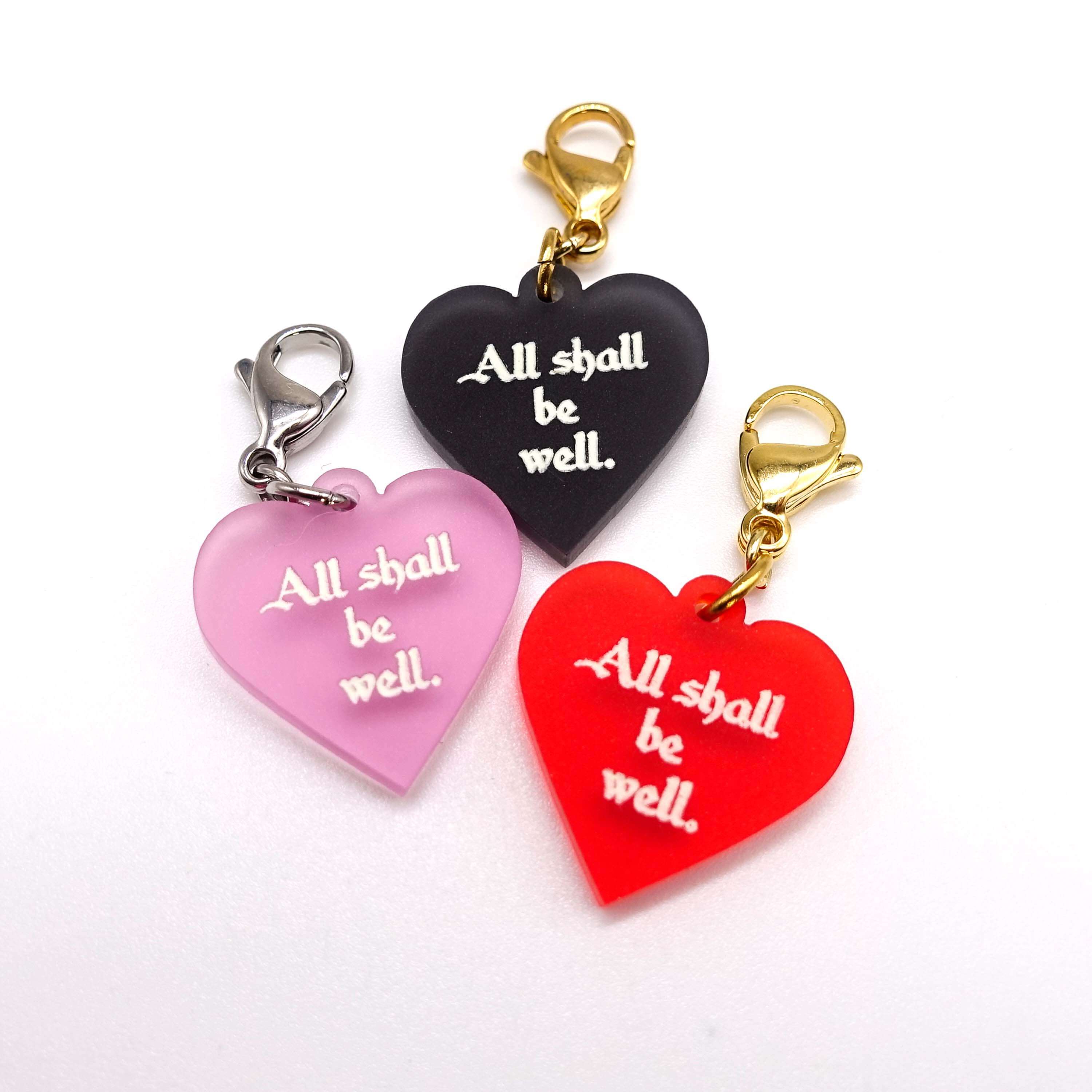 Heart charms etched and hand-painted with the words All shall be well in glow in the dark pigment.