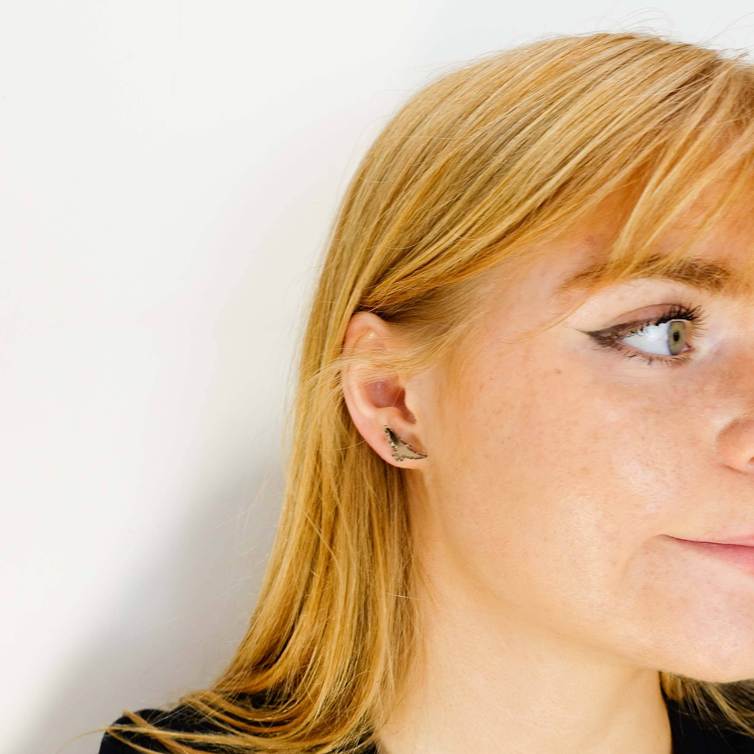 Eliza wears little bronze bird stud earrings from the Brontë Collection, designed by Sarah Day in collaboration with the Brontë Parsonage Museum. 