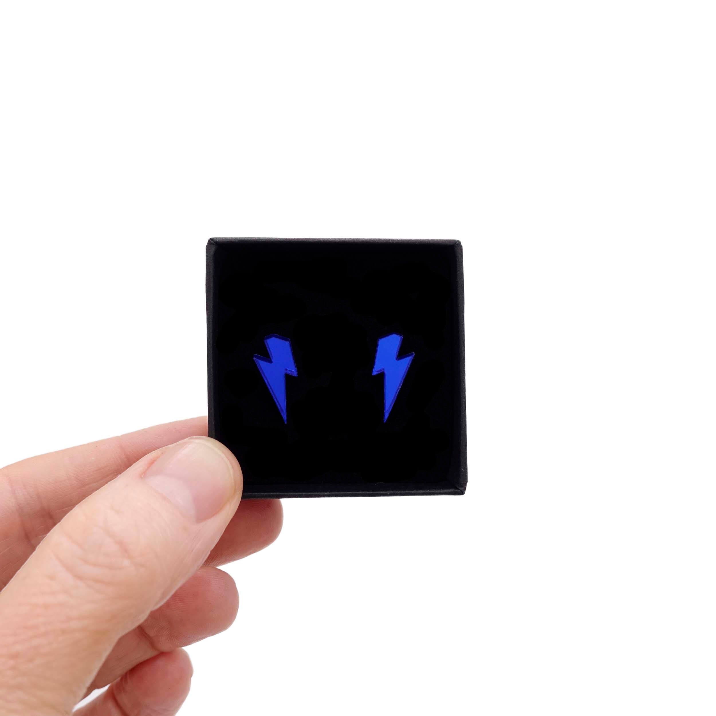 Tiny Lightning Bolt earrings in electric blue mirror, shown held up in a small Wear and Resist gift box.