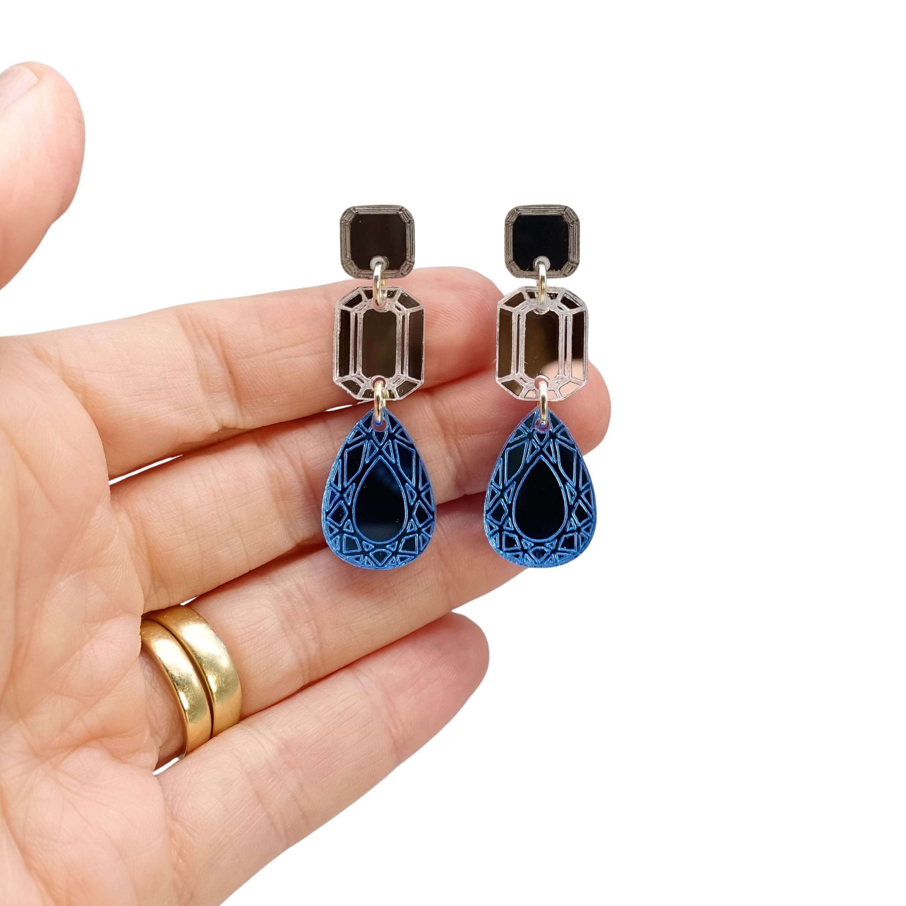 Belle epoque medium earrings in cool blue: bronze, silver and sky, shown hanging with my hand behind for scale.