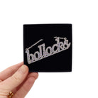 Bollocks necklace in silver glitter shown in a Wear and Resist gift box.