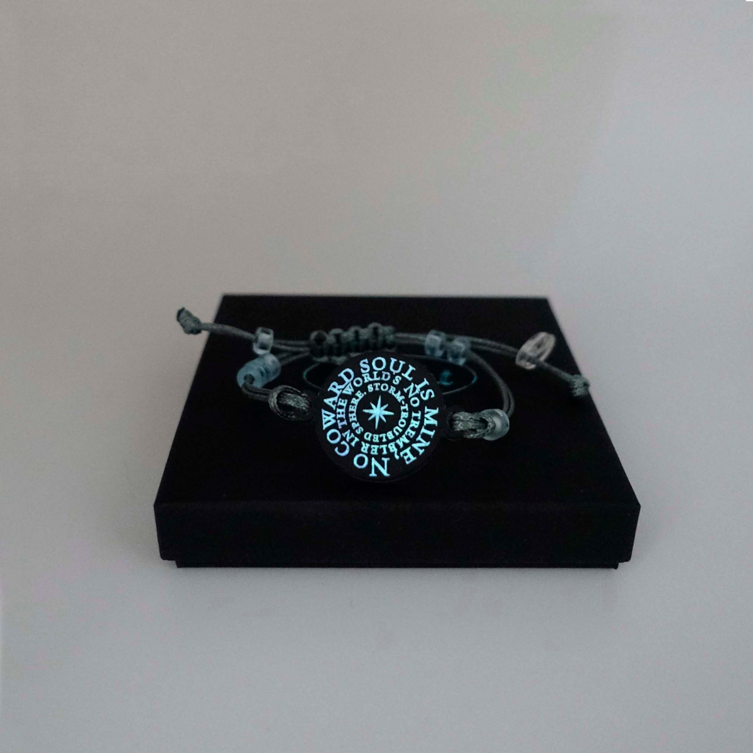 The No Coward Soul is Mine bracelet glowing in the dark on a Wear and Resist gift box. From the Brontë Collection. 