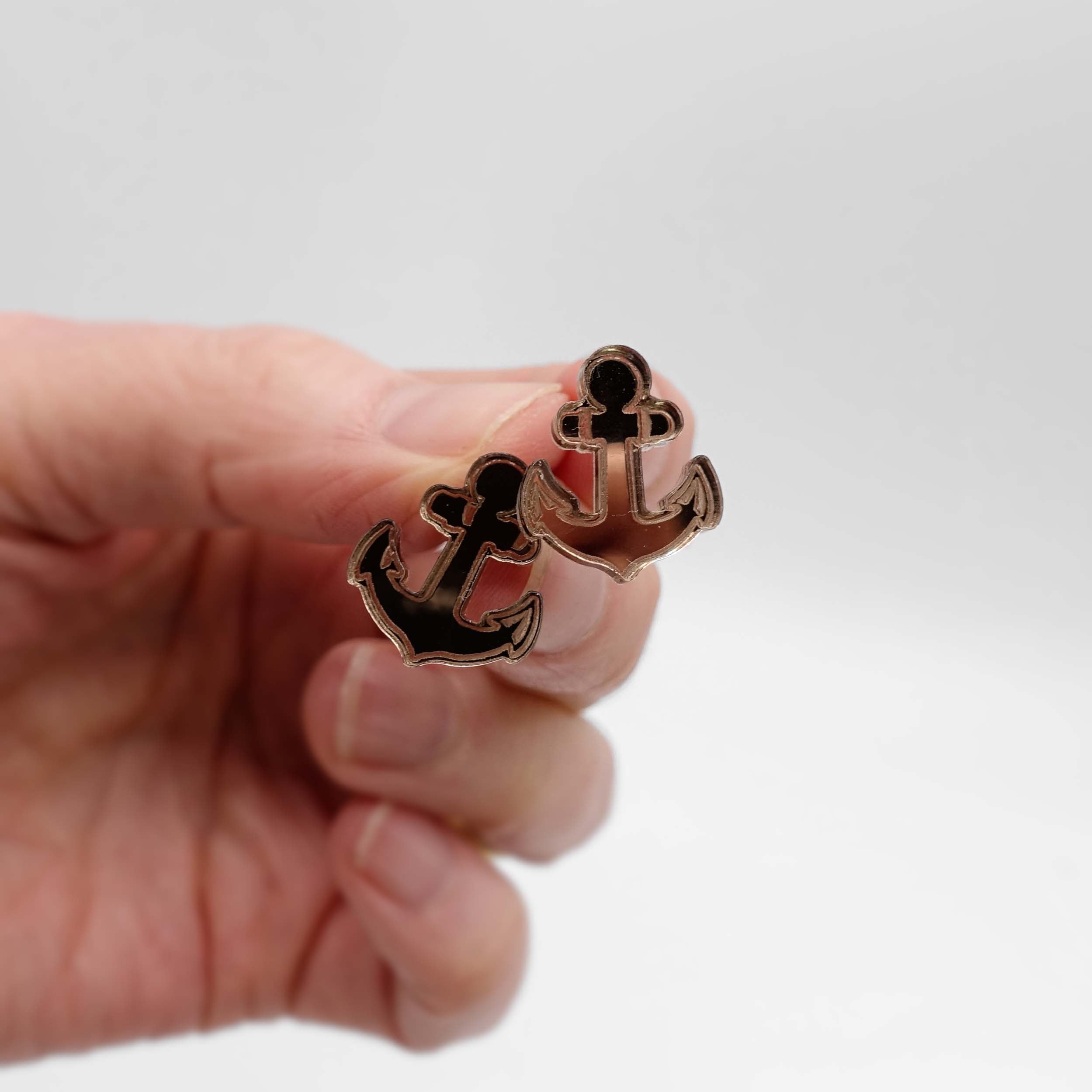 Bronze mirror little anchor earrings shown held up for scale against a white background. 