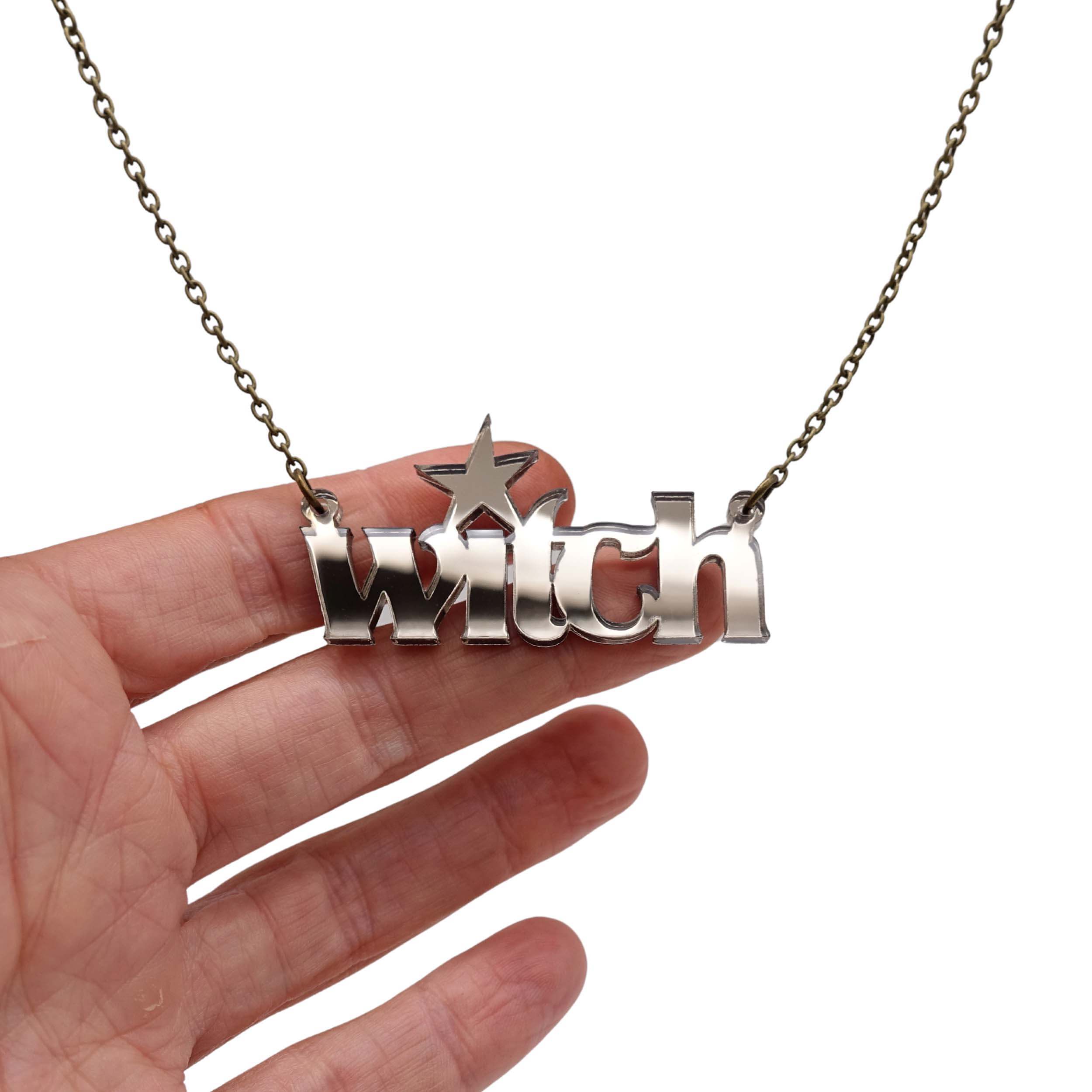 Witch necklace in bronze mirror shown hanging against a white background with my hand for size.