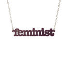 Cassis Feminist necklace shown hanging on a white background.